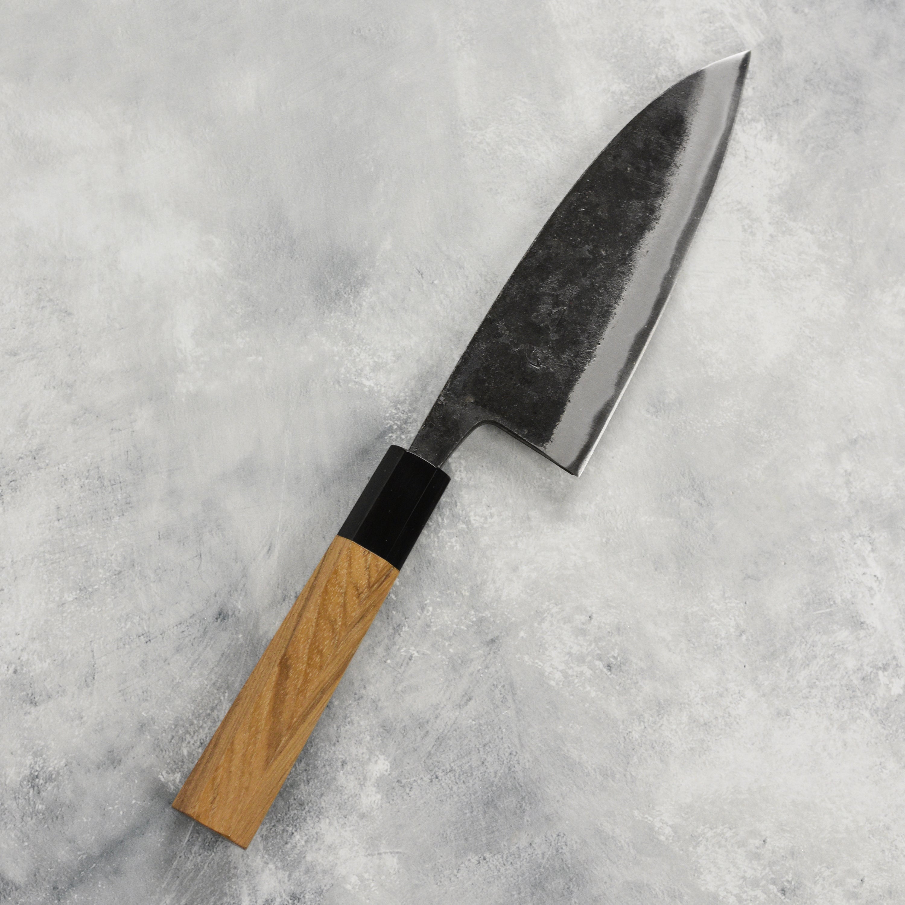 Hatsukokoro Kurokaze Aogami Deba Knife in use, expertly slicing sushi ingredients on a wooden cutting board.