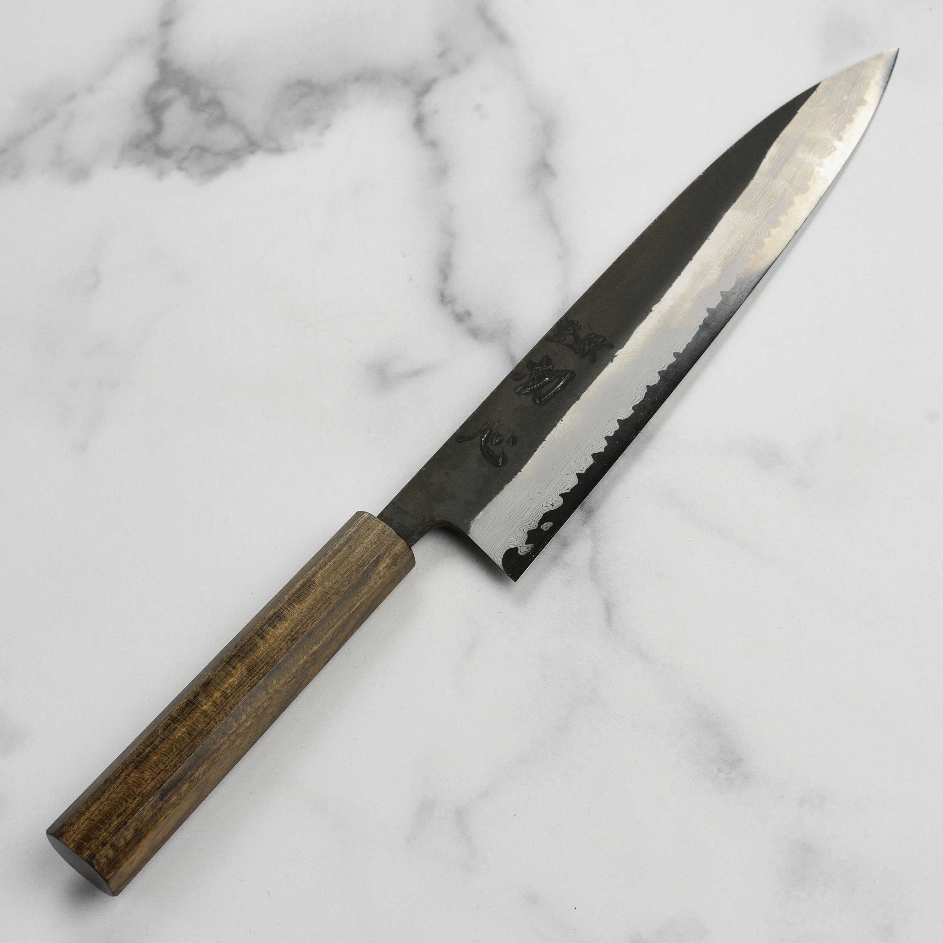Close-up of the Damascus steel blade, highlighting kurouchi finish and craftsmanship