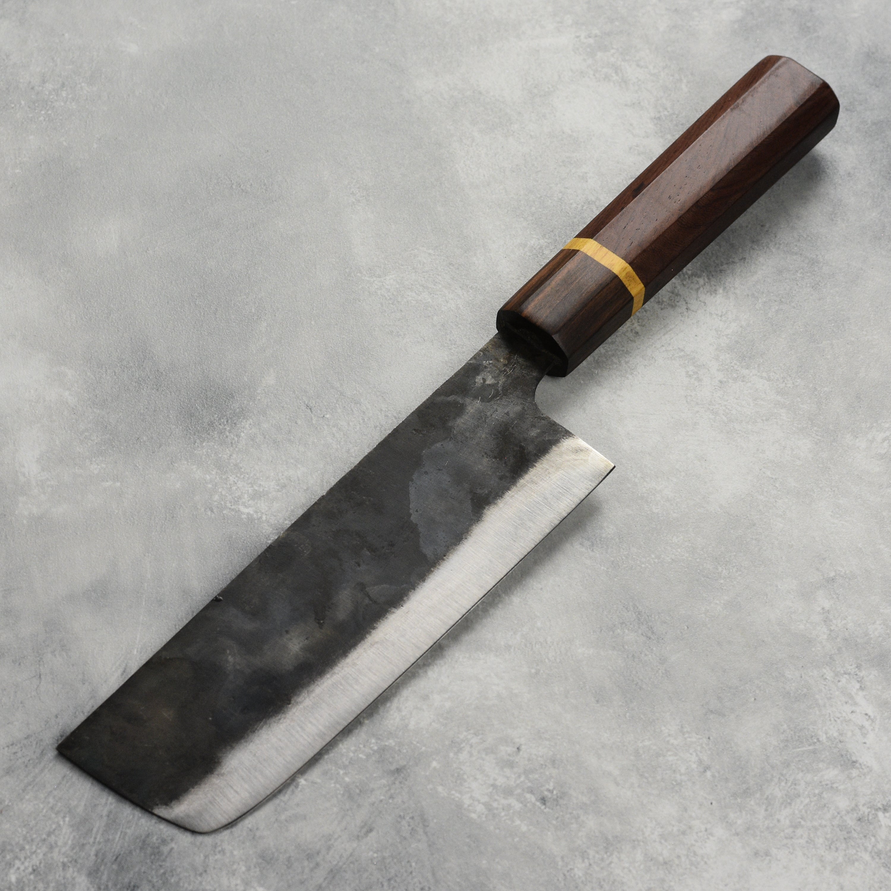 Top view of 6.5-inch carbon steel nakiri knife slicing vegetables in a kitchen setting