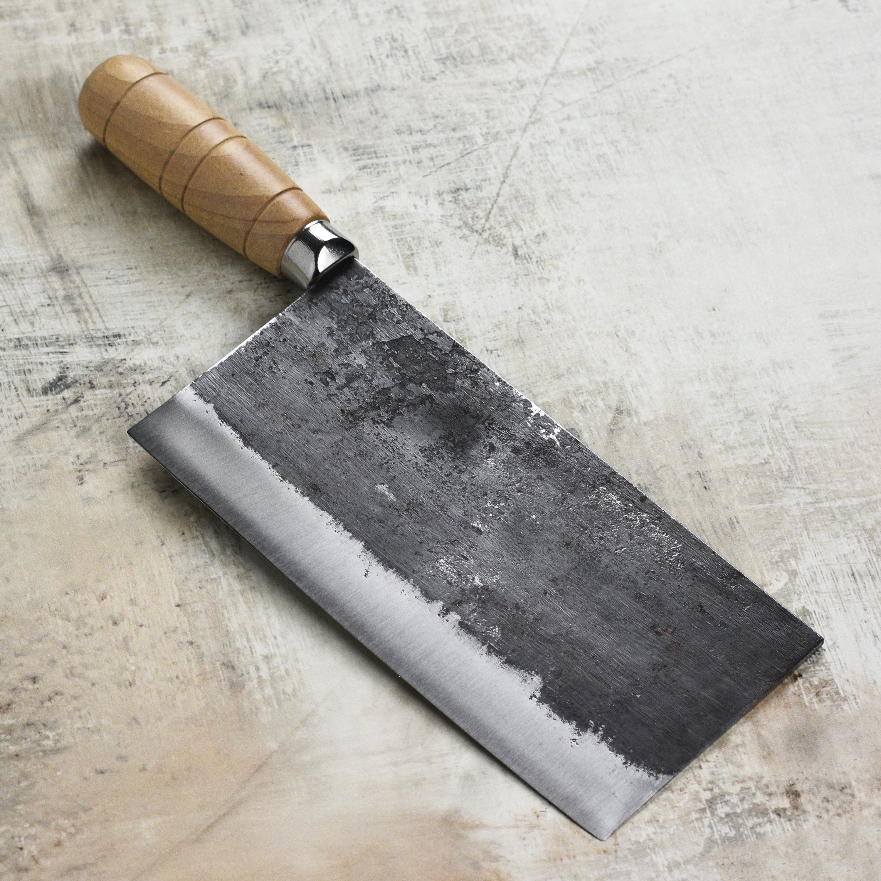 Top-down view of the Rustic Hand-Forged Carbon Steel 8" Chinese Cleaver on a cutting board, perfect for slicing vegetables.