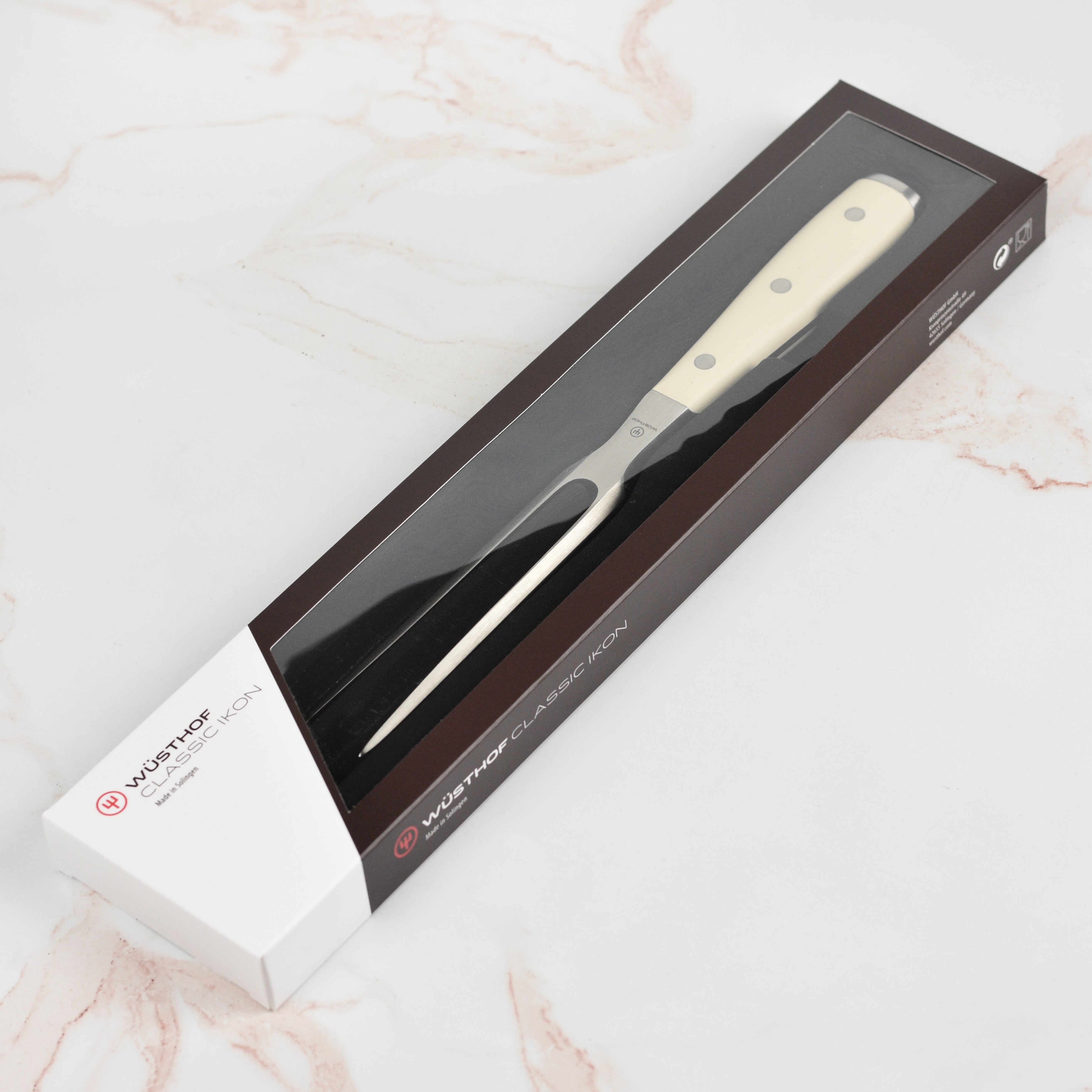 Side view of Wusthof Classic Ikon Creme carving fork next to roast beef