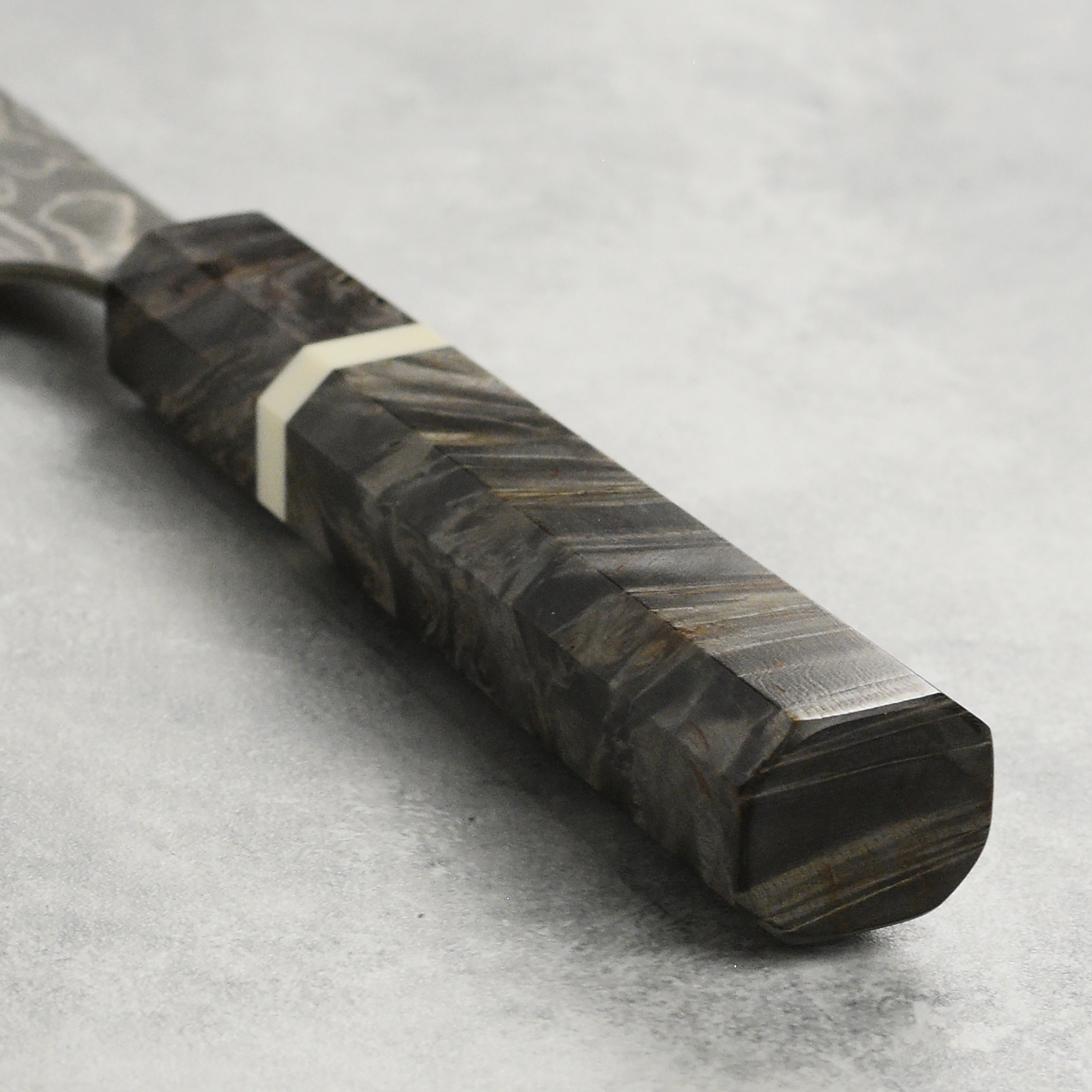 Close-up of the SG2 Damascus steel blade showcasing its fine edge and stunning dark finish.