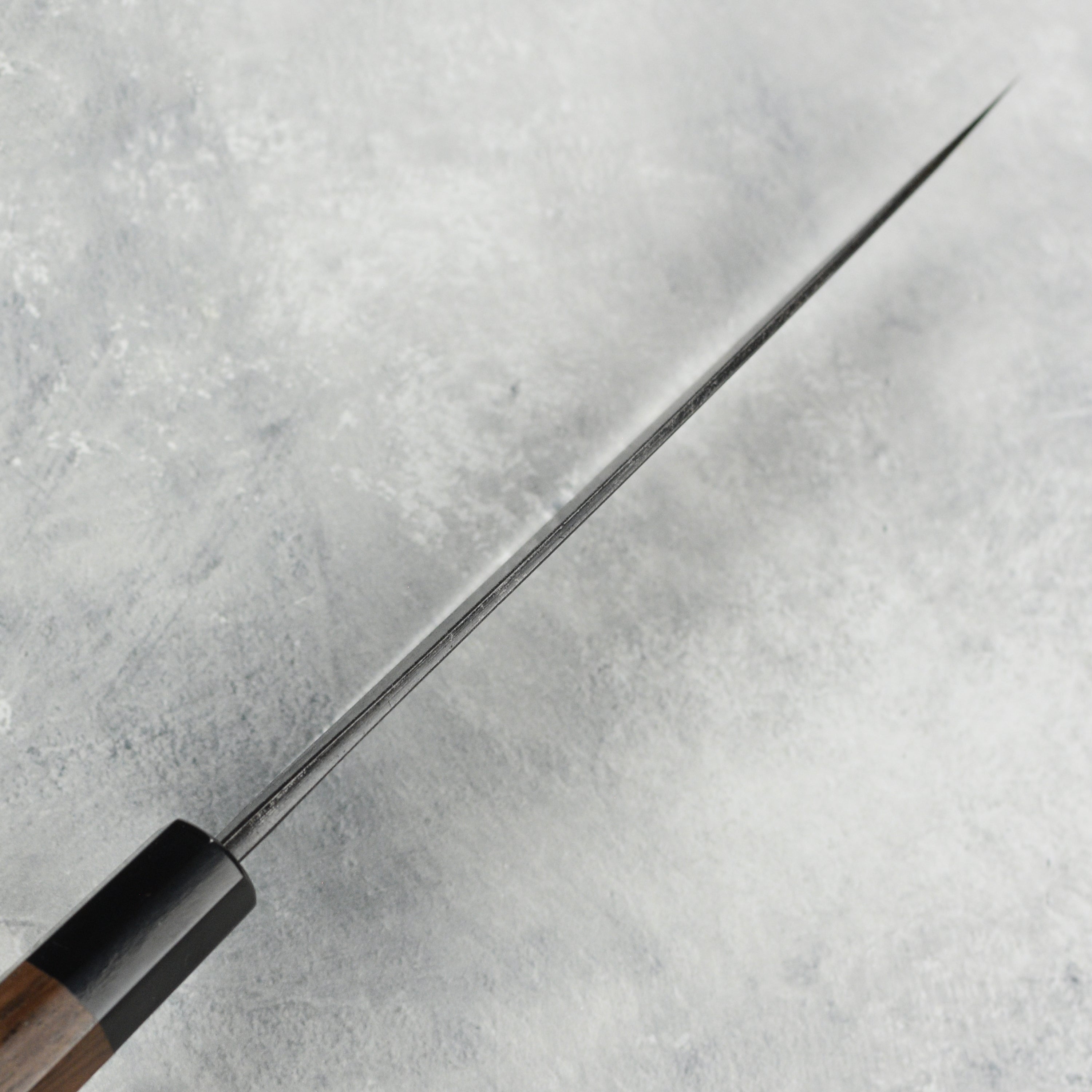 Detailed view of the ergonomic handle of the Hatsukokoro Damascus knife, emphasizing comfort and control.