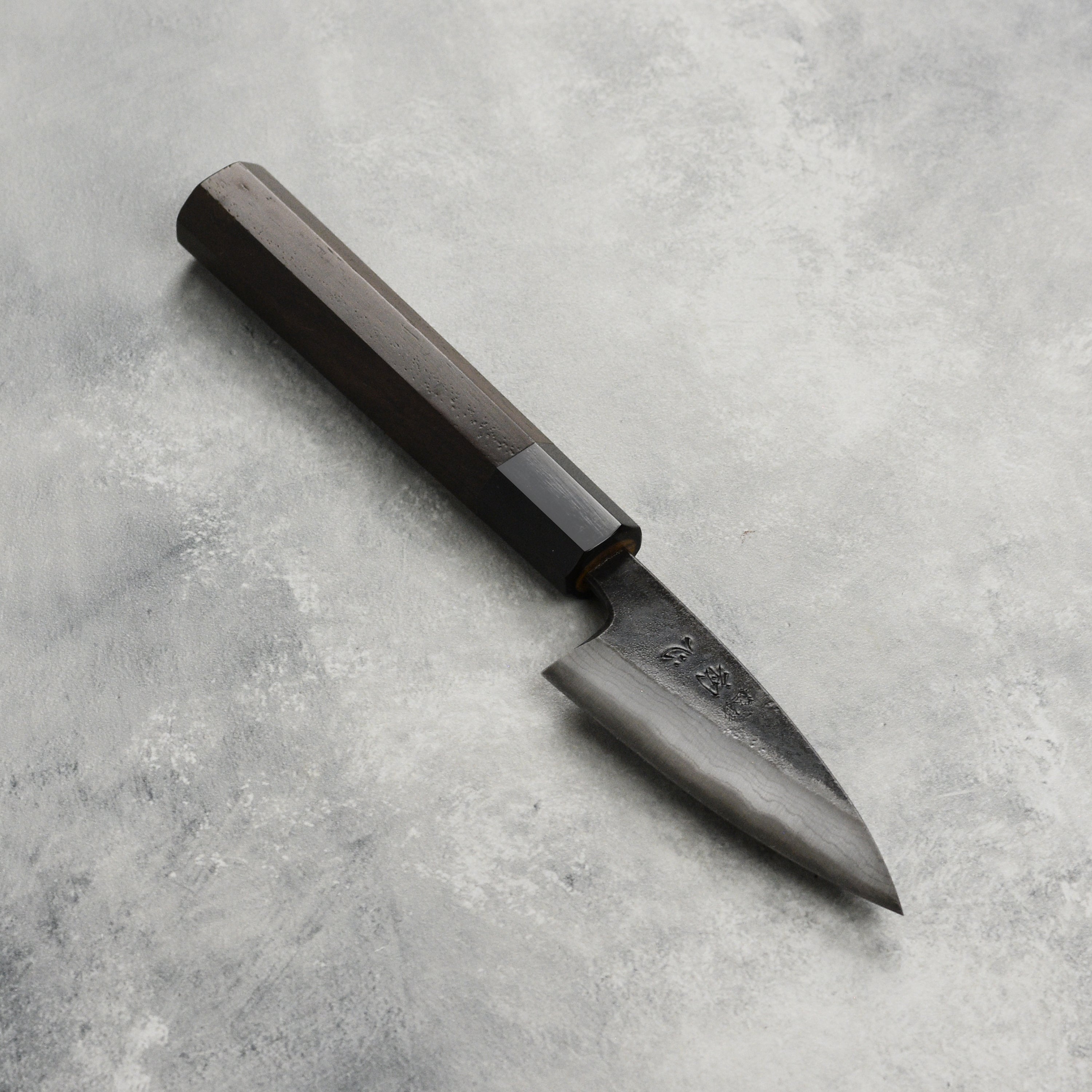 Side view of the Hatsukokoro Damascus petty knife highlighting its Kurouchi finish and sharp edge