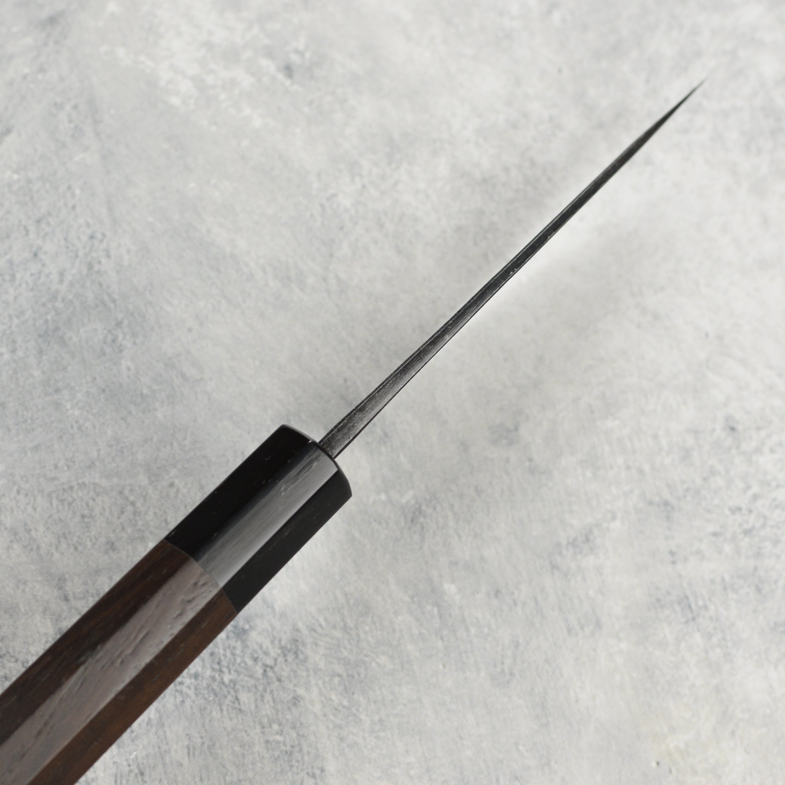 Side view of the Hatsukokoro Damascus petty knife highlighting its Kurouchi finish and sharp edge