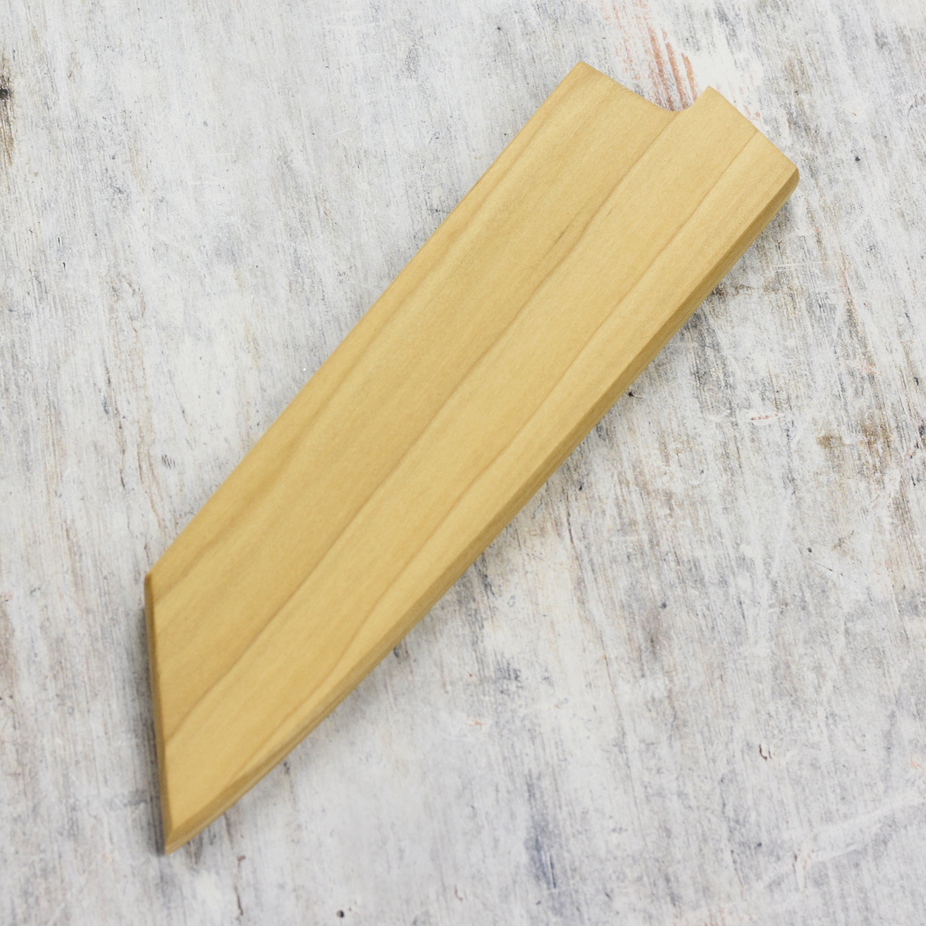 Close-up of magnetic knife cover holding a Japanese chefs blade inside the wooden saya