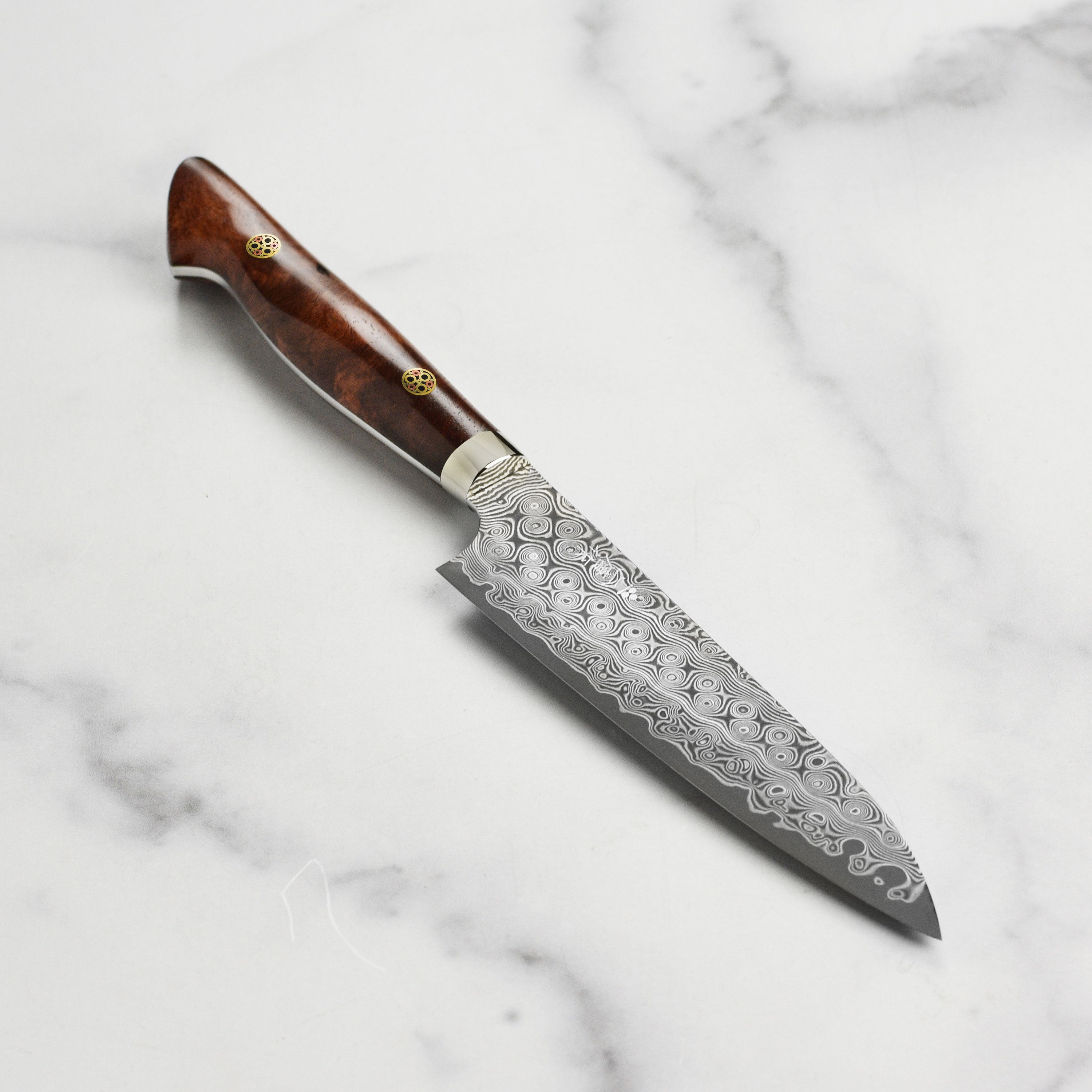 Nigara Anmon SG2 Damascus petty knife with quince wood handle on a wooden cutting board