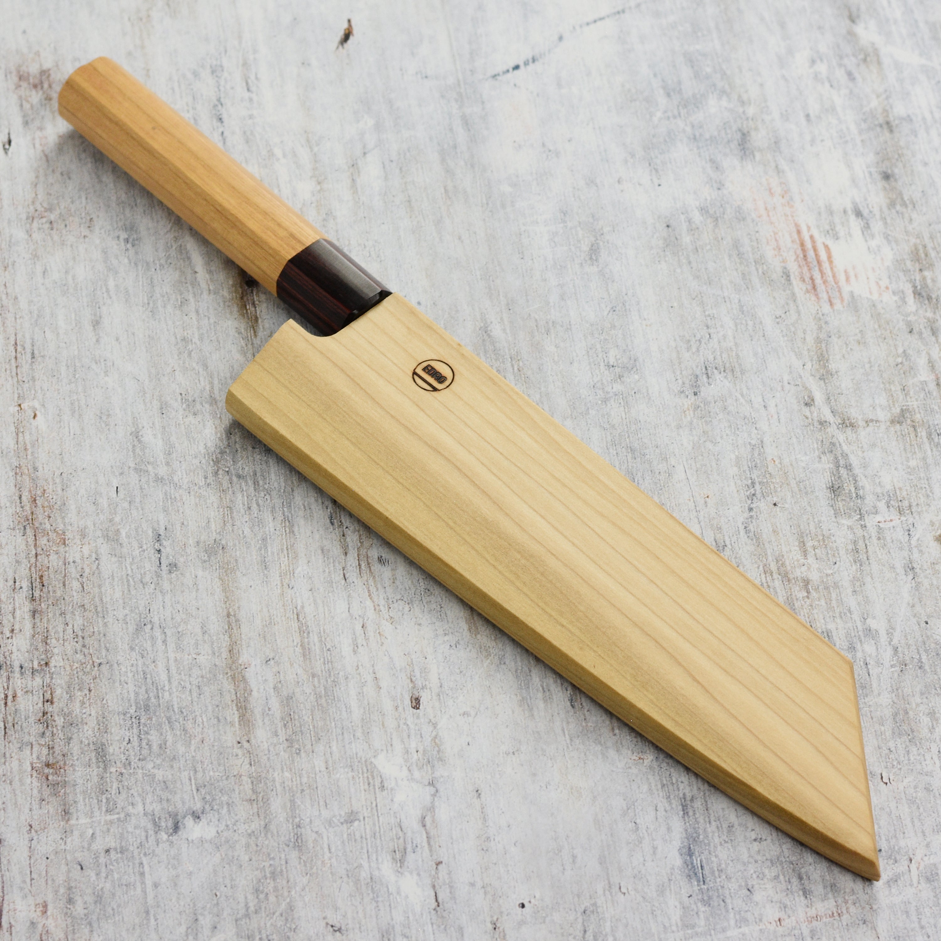 Close-up of magnetic knife cover holding a Japanese chefs blade inside the wooden saya