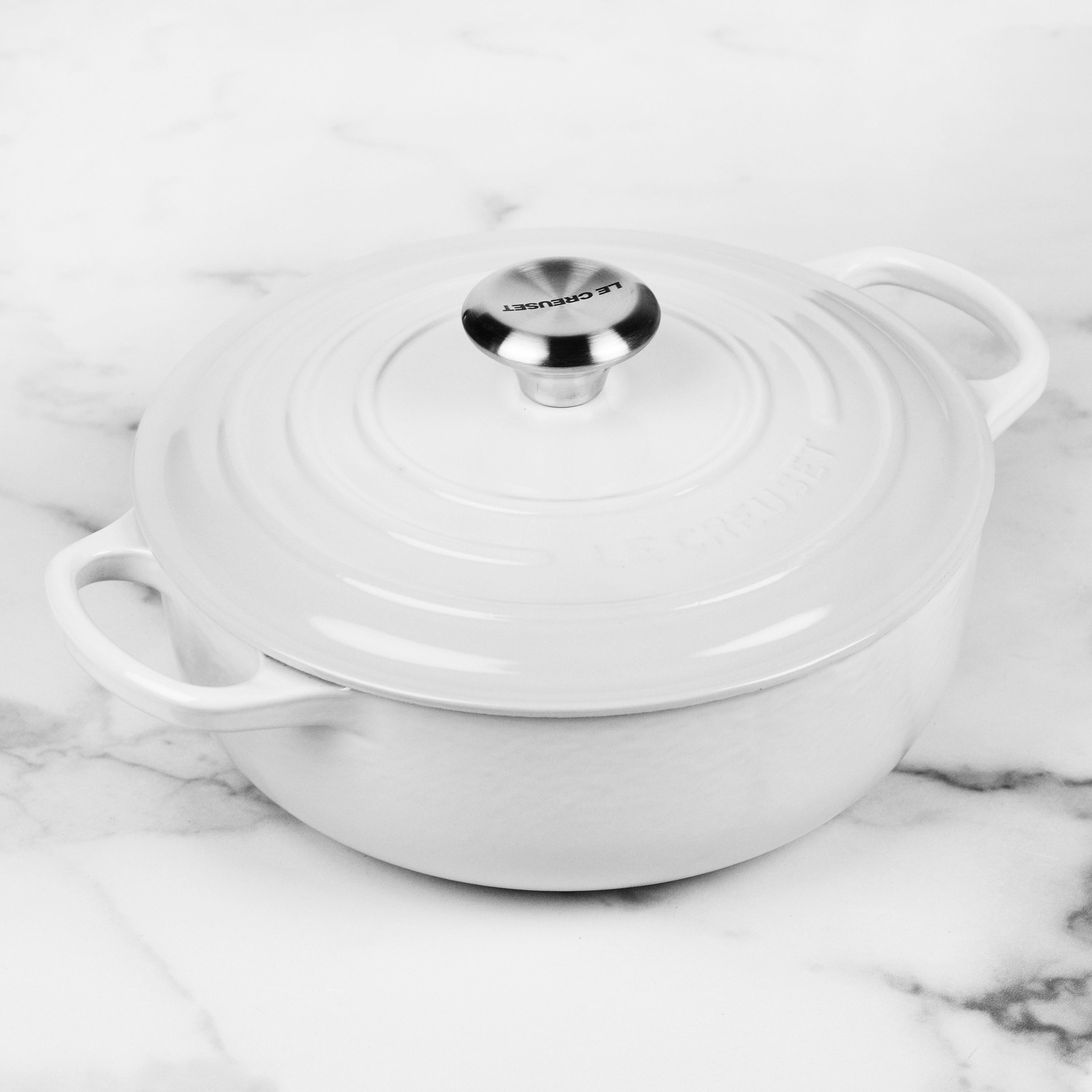 Le Creuset white cast iron Dutch oven with lid and handles, ideal for slow cooking and roasting