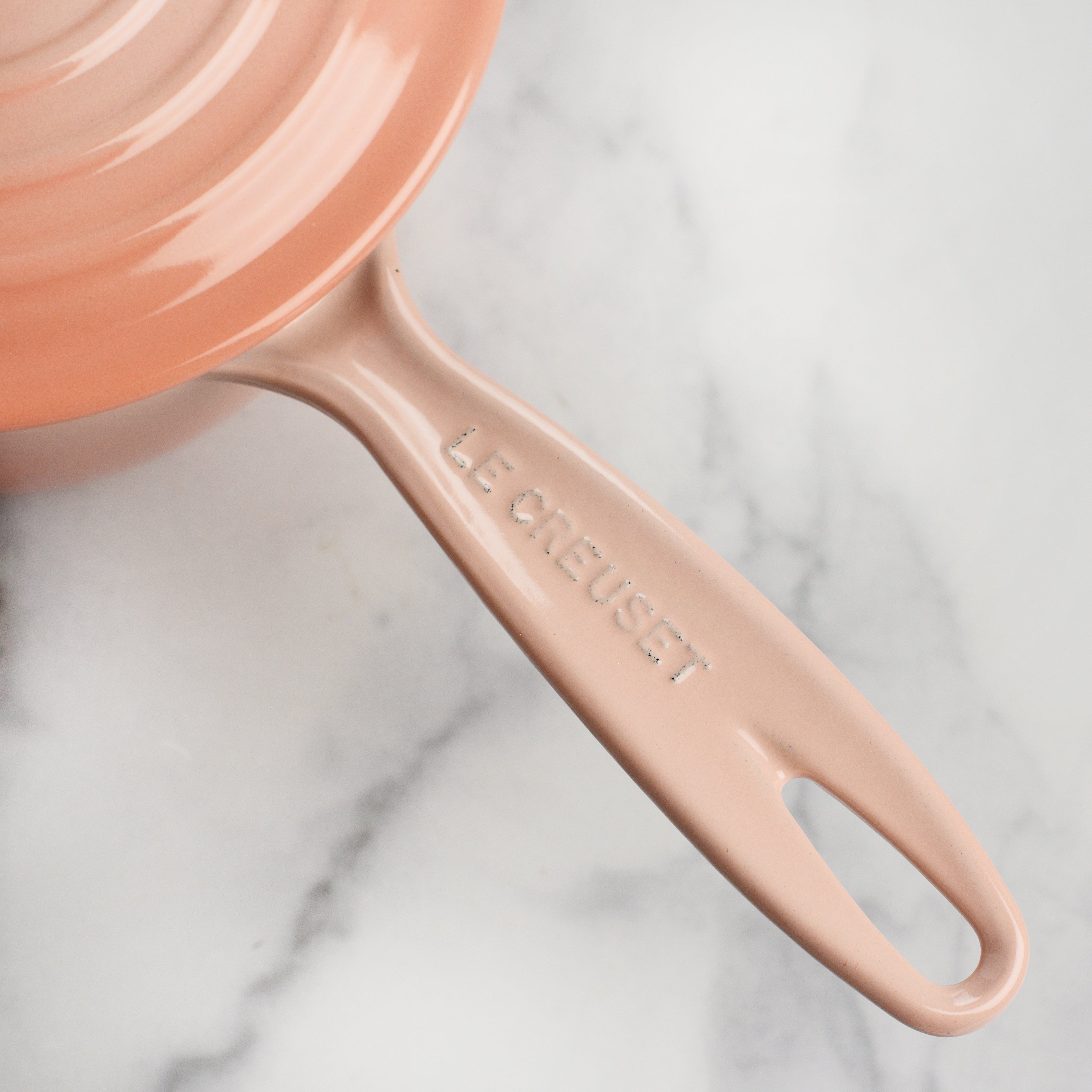 Close-up of Le Creuset enameled cast iron saucepan with lid, showcasing its durable finish.