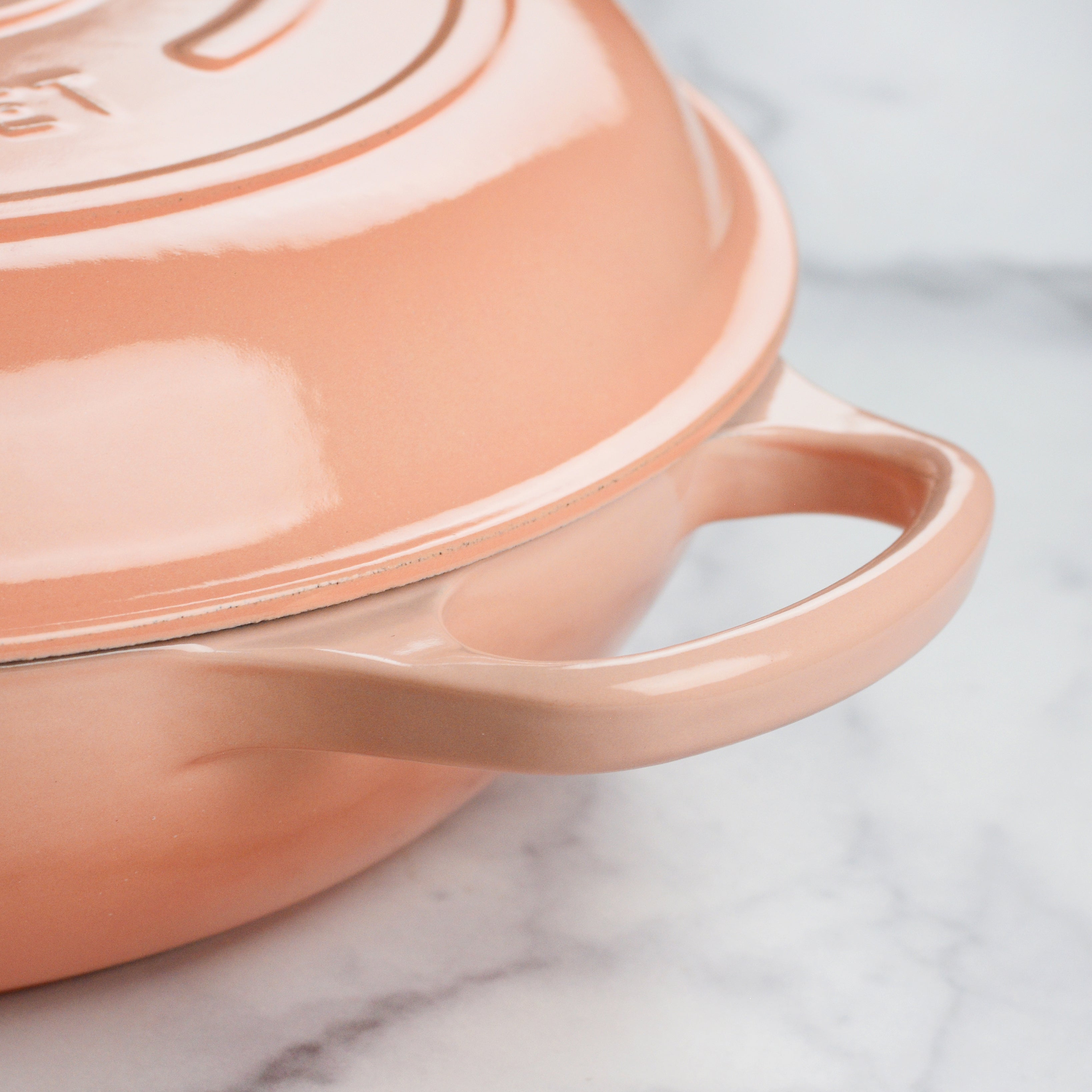 A close-up of the light gold stainless steel knob on the Le Creuset braiser, emphasizing its functional design.