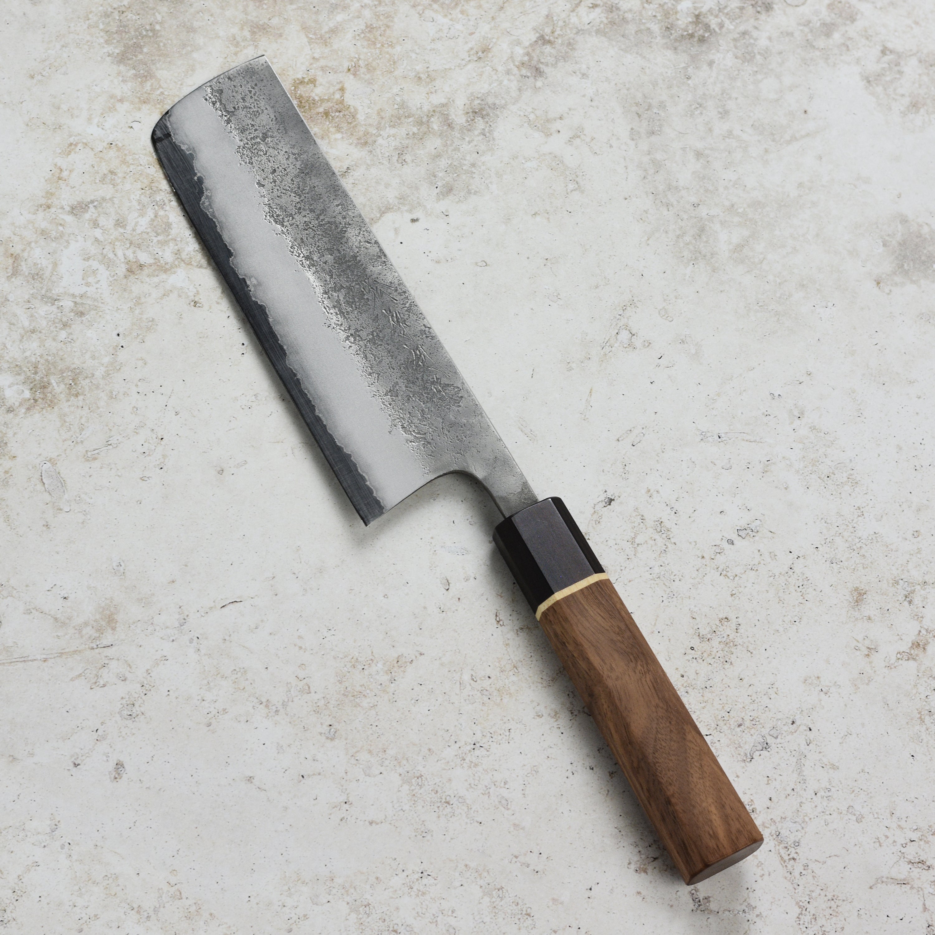 Close-up of the Aogami Nakiri knife demonstrating precision cuts on fresh vegetables.