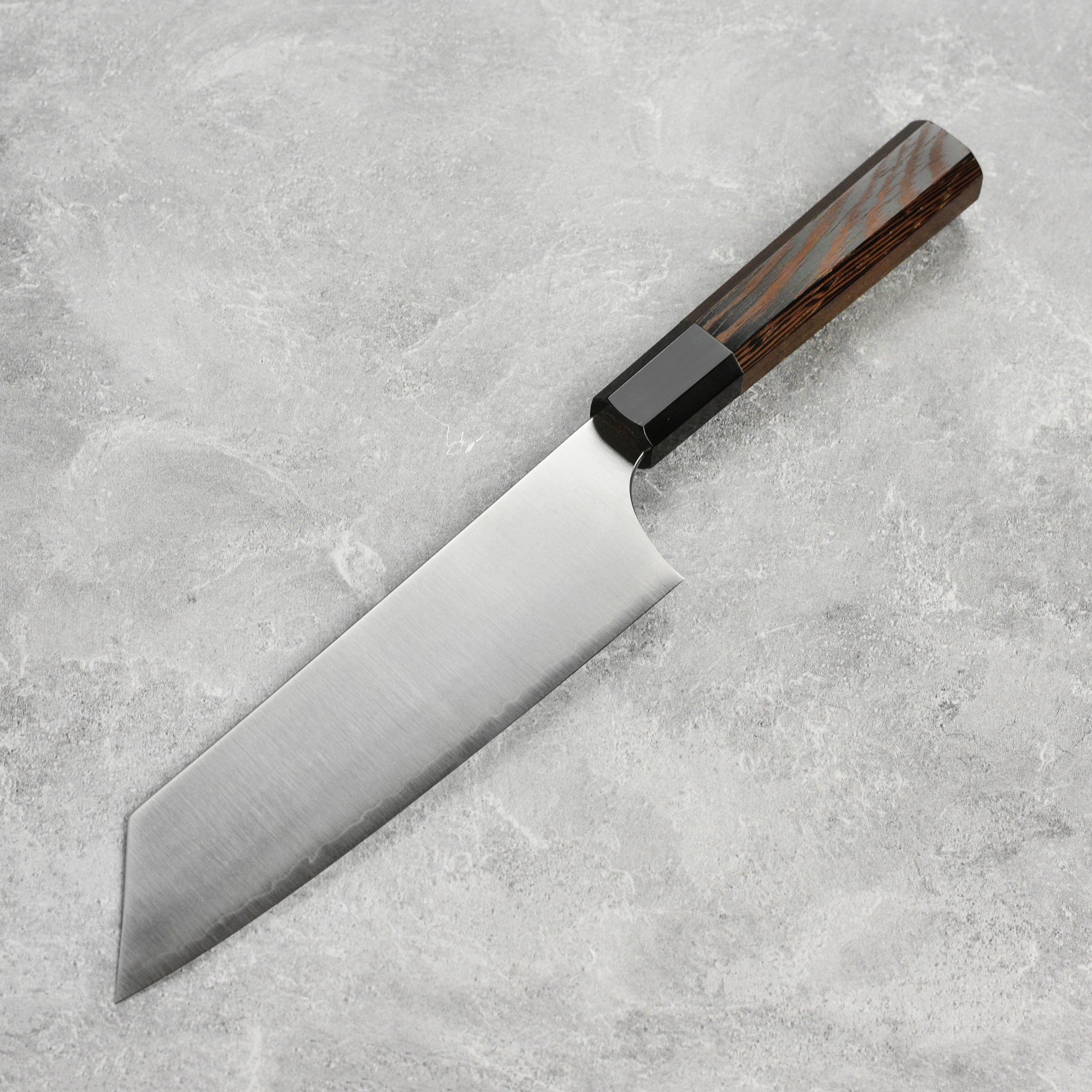 Hatsukokoro Hayabusa Aogami Super Bunka Knife in action, slicing vegetables on a wooden cutting board.