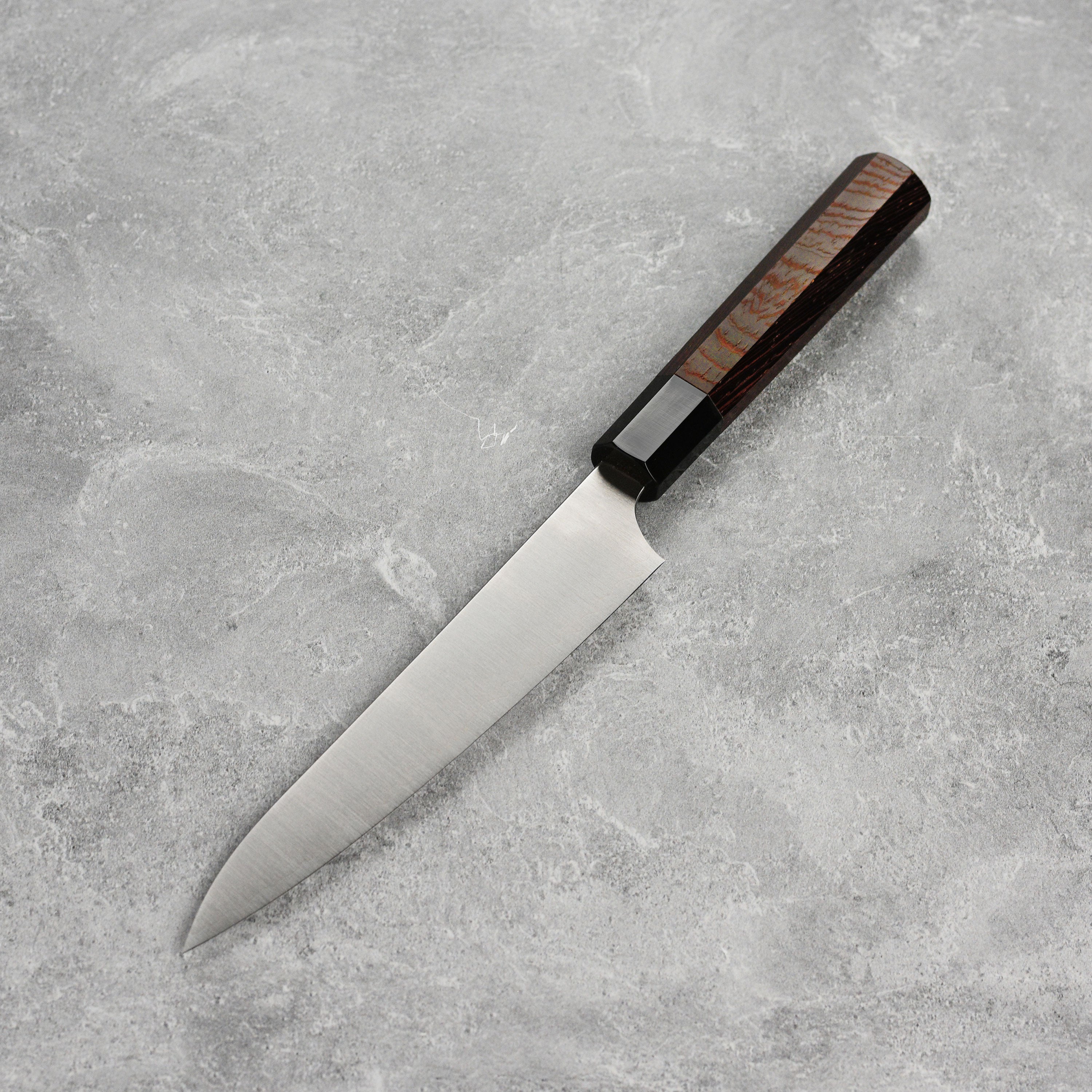 Close-up view of the Hatsukokoro Aogami Super petty knife blade, highlighting its sharp edge and craftsmanship.