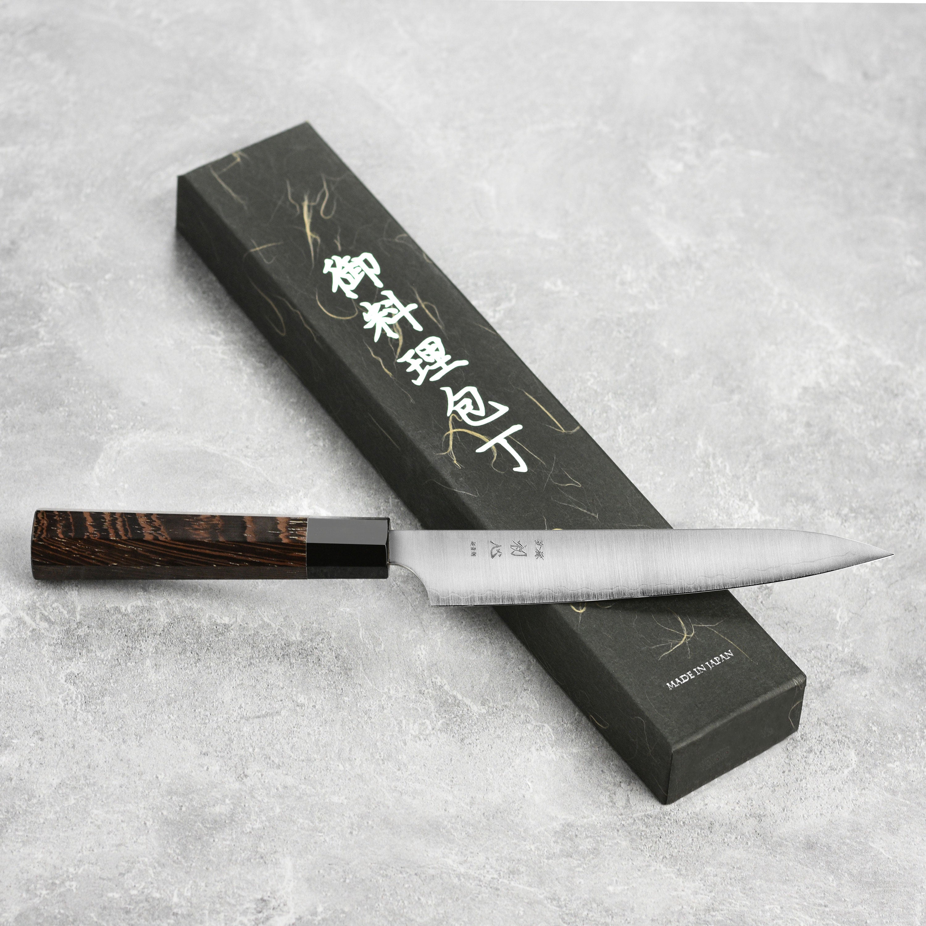 Chef using the Hatsukokoro Aogami Super petty knife in a kitchen setting, demonstrating its precision cutting capabilities.