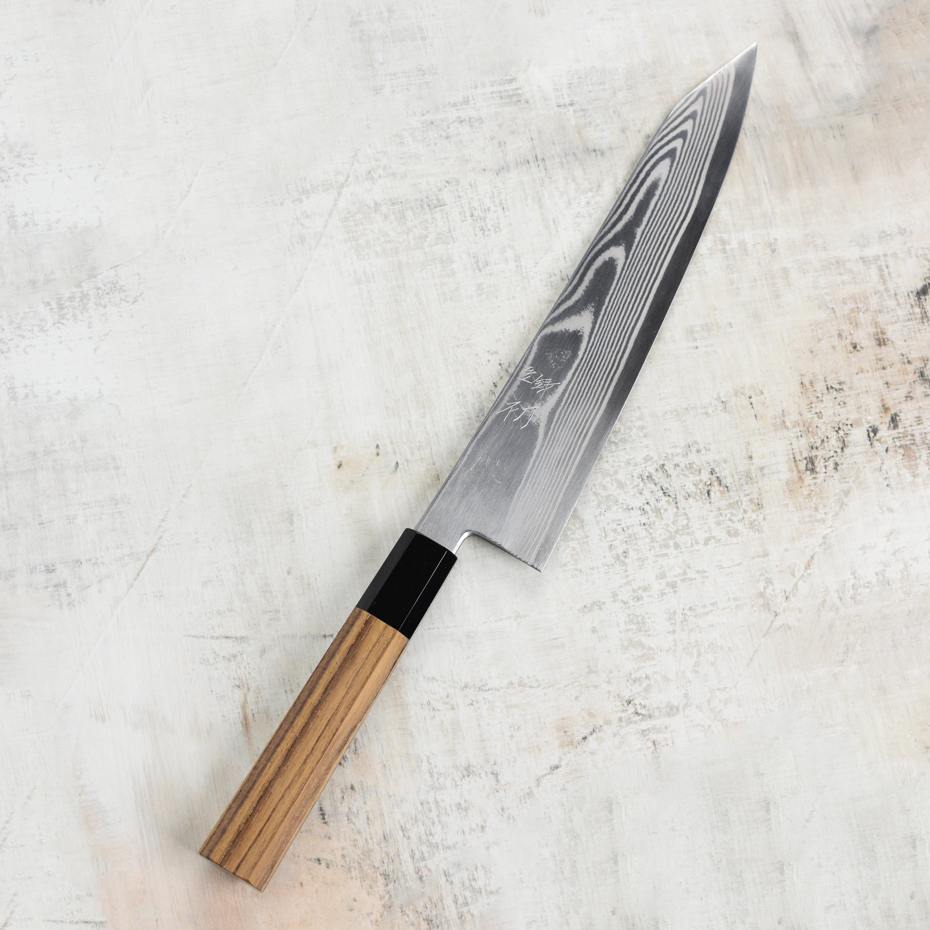 Hatsukokoro Ginsou Damascus Gyuto Chef Knife in action, slicing fresh vegetables on a cutting board.