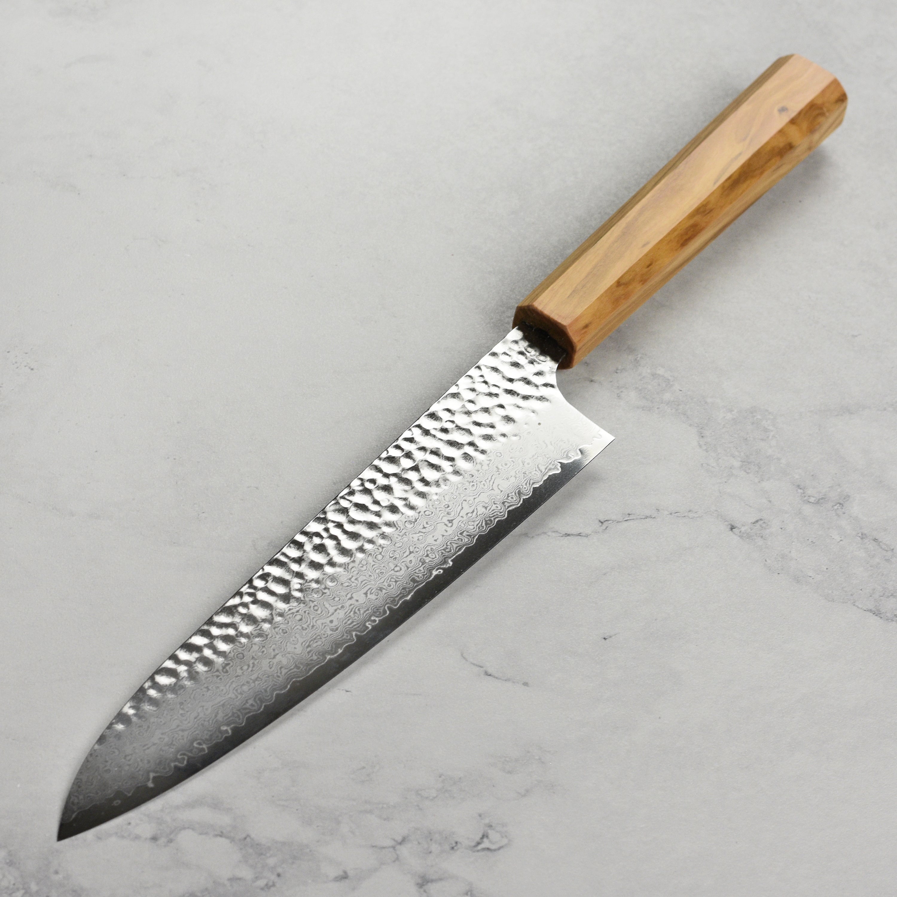 Close-up of Japanese chef knife blade and olivewood handle with detailed craftsmanship