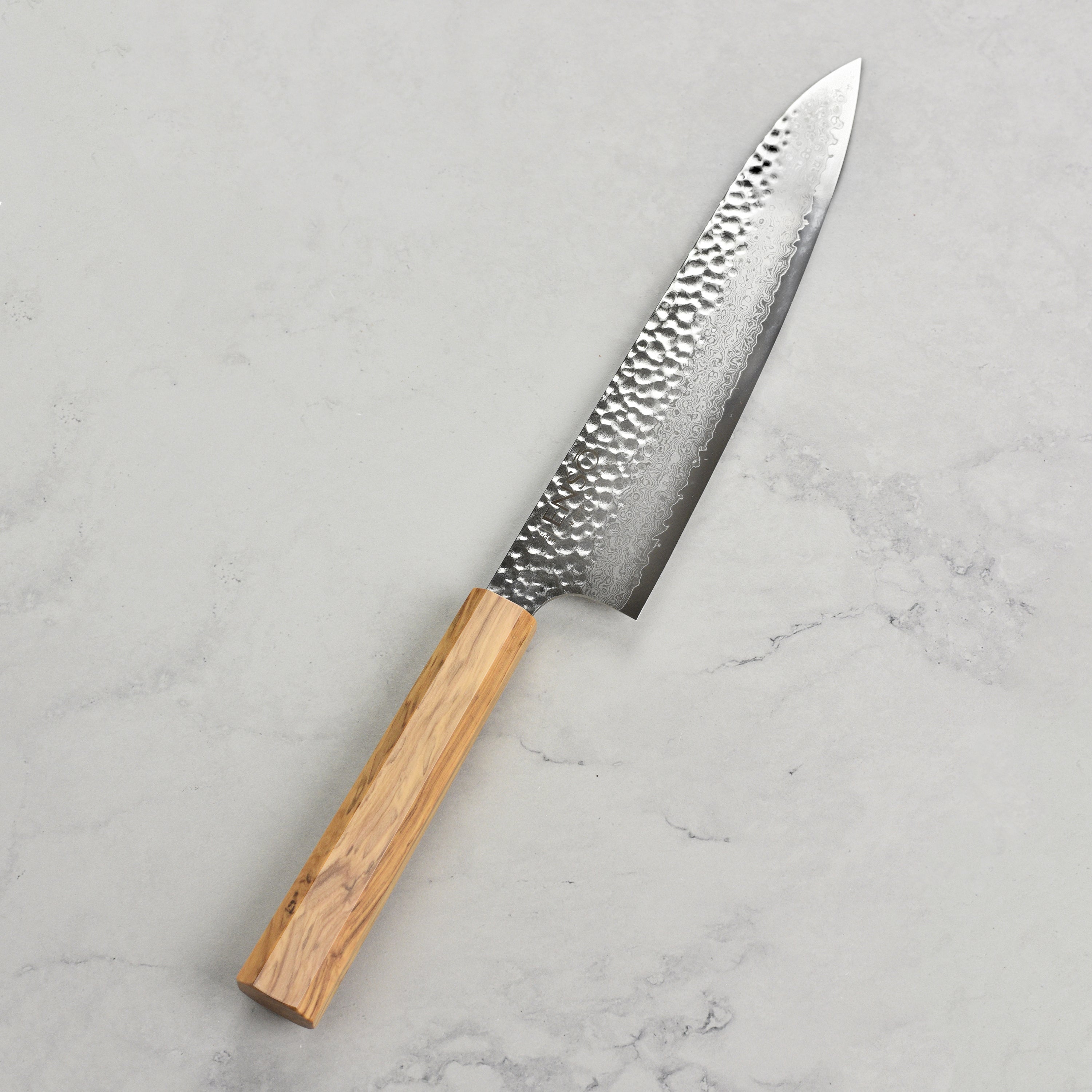 Professional chef knife in use chopping vegetables with ergonomic olivewood handle