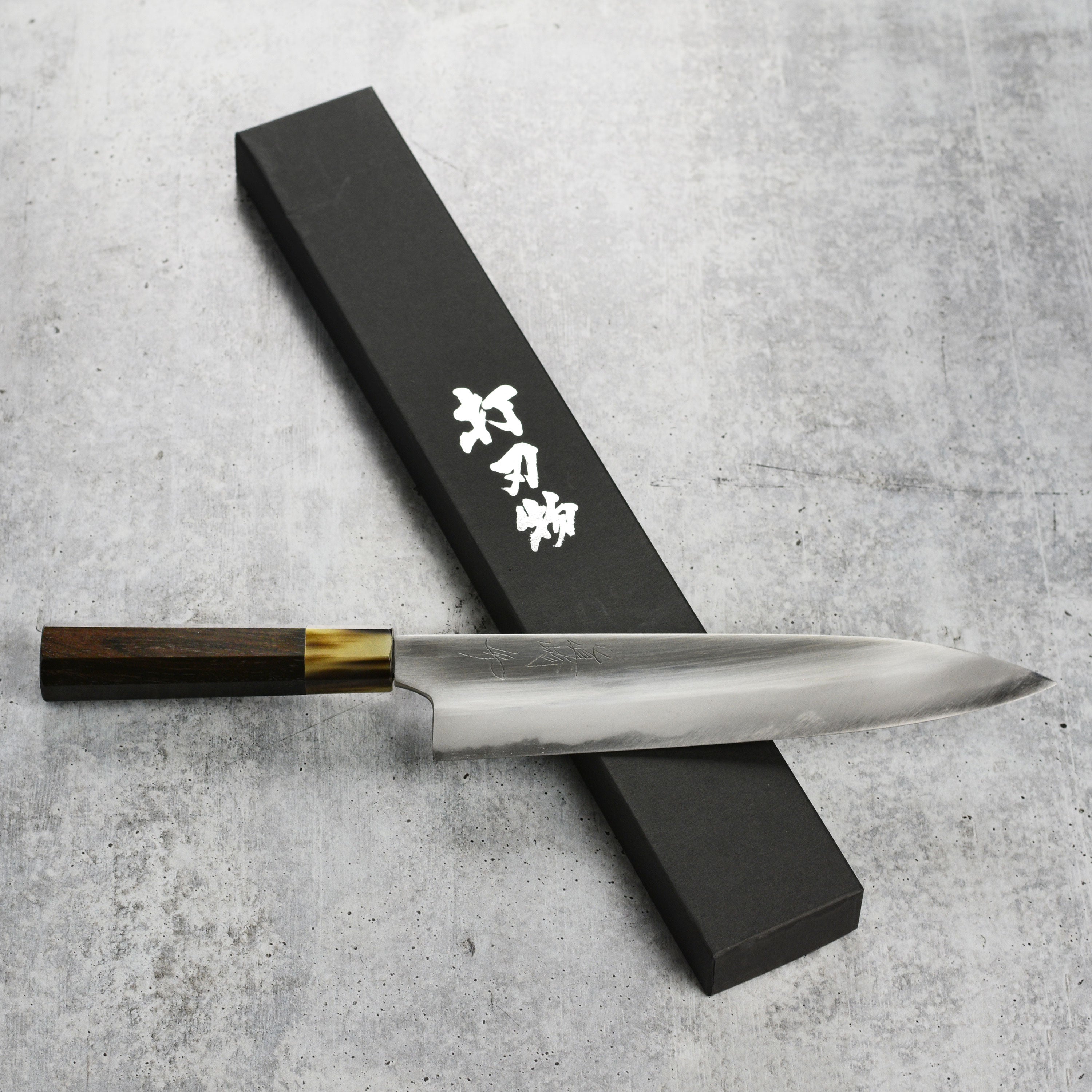 Mazaki gyuto knife slicing vegetables on a wooden cutting board