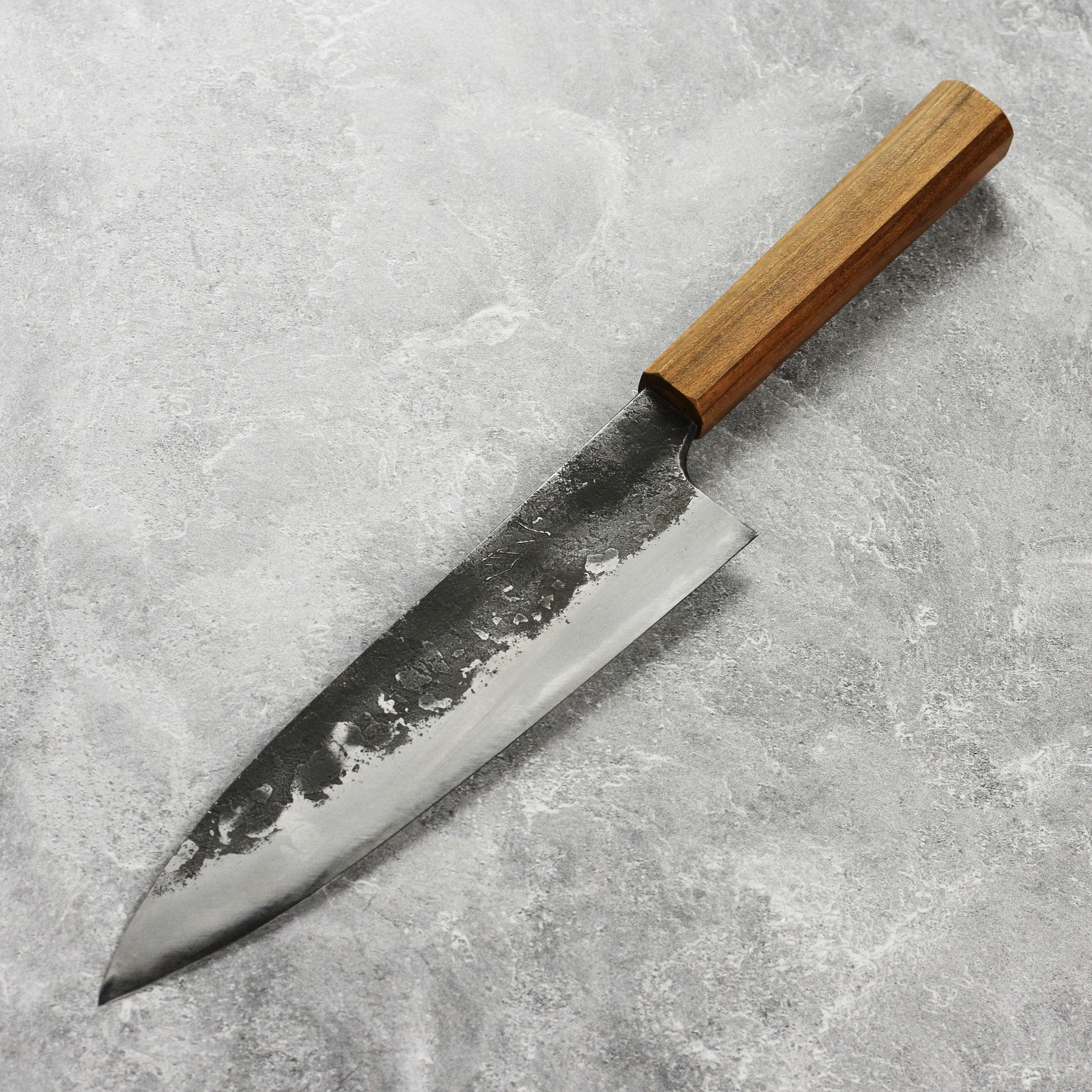 Side view of the Mazaki Shirogami Kurouchi Gyuto knife displaying its unique Kurouchi finish and ergonomic handle.