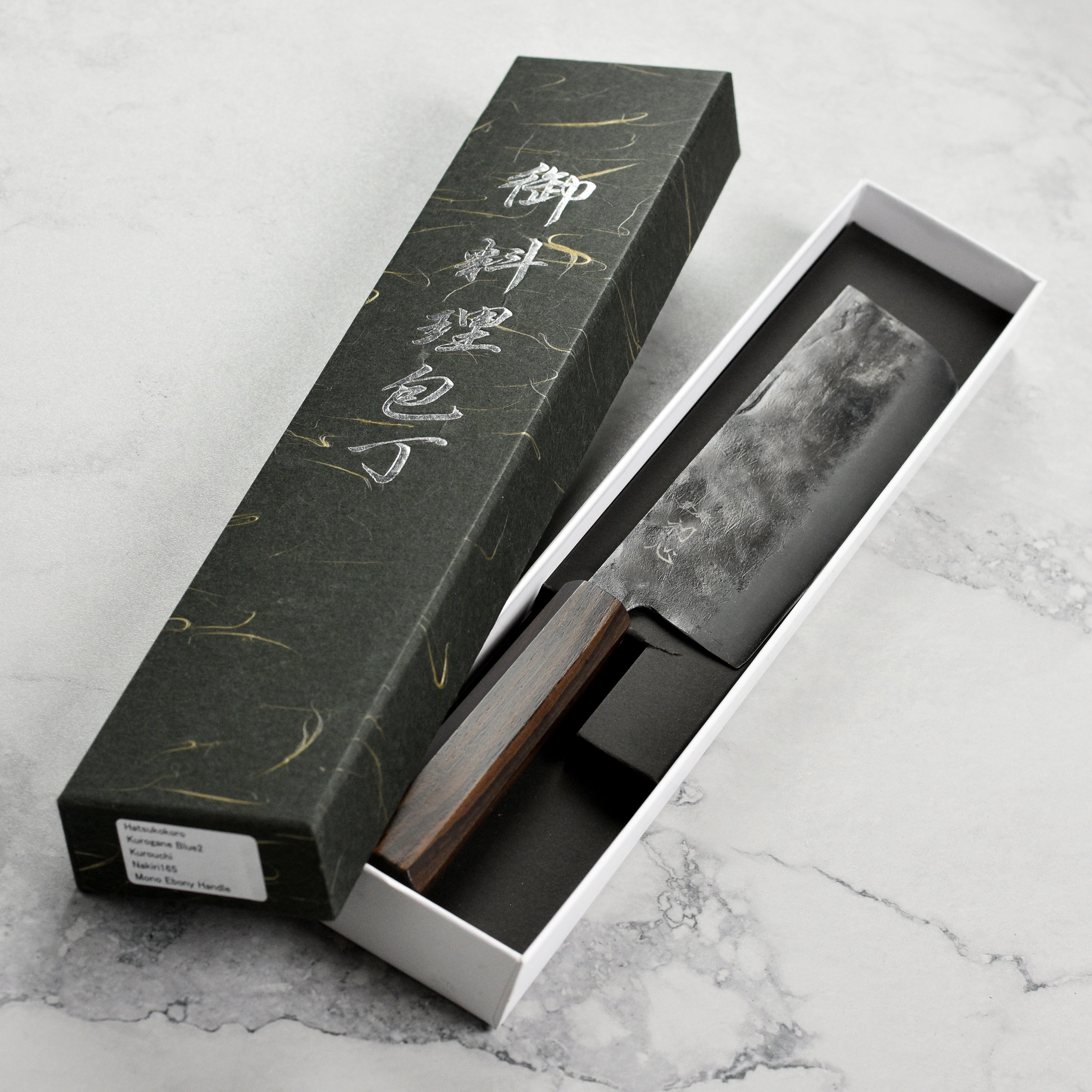 Hatsukokoro Nakiri knife showcasing its Aogami #2 Kurouchi blade on a kitchen table.