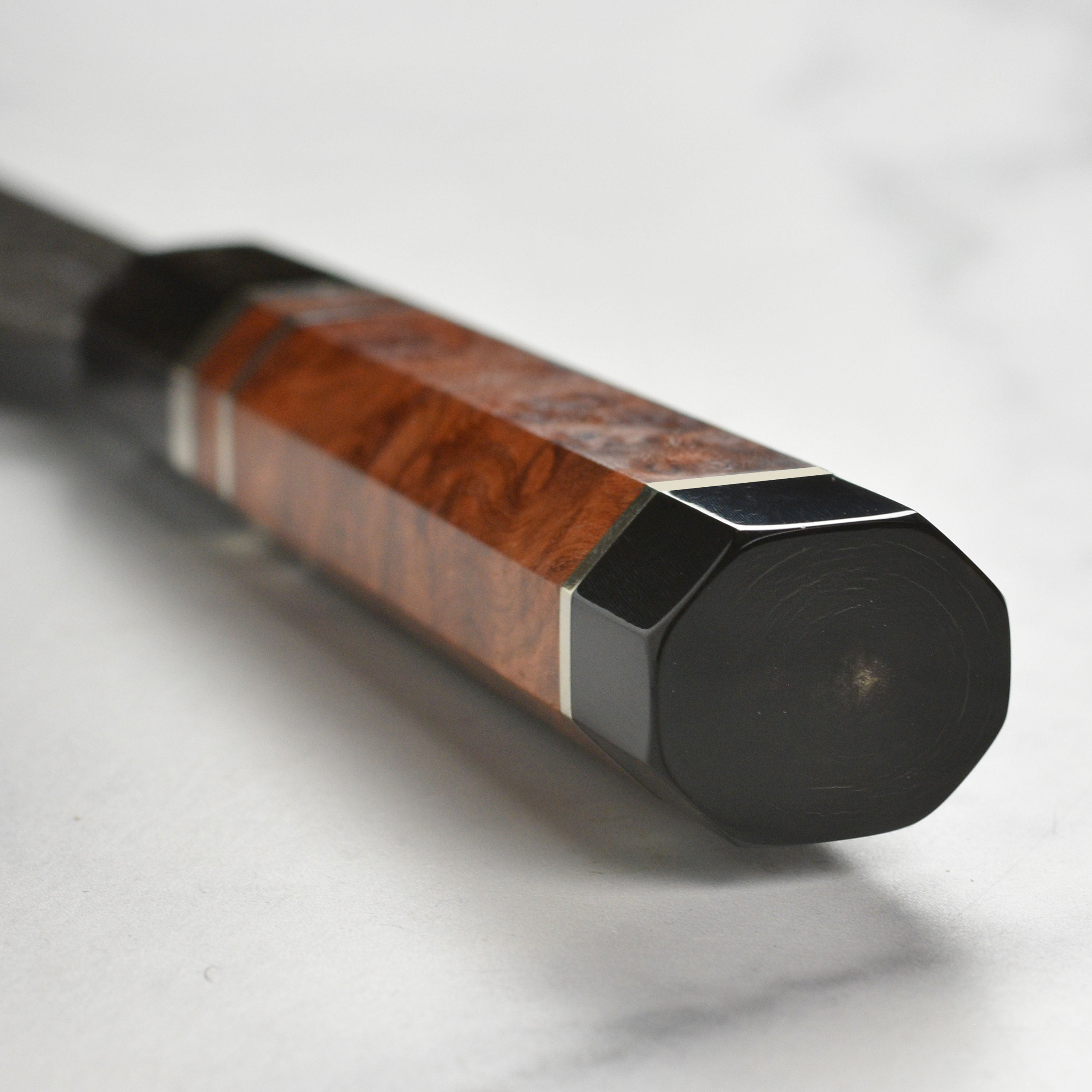 Side view of the 9.4" Japanese chef knife resting on a cutting board with fresh vegetables