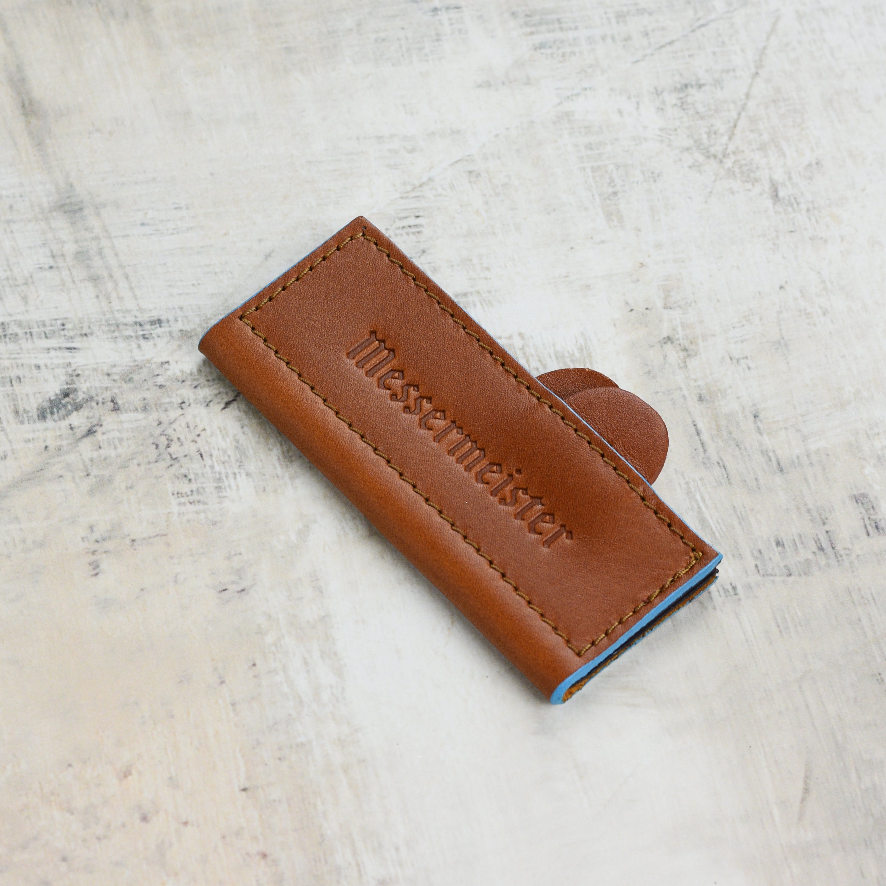 Close-up of the saddle brown leather knife guard showing the magnetic closure feature.