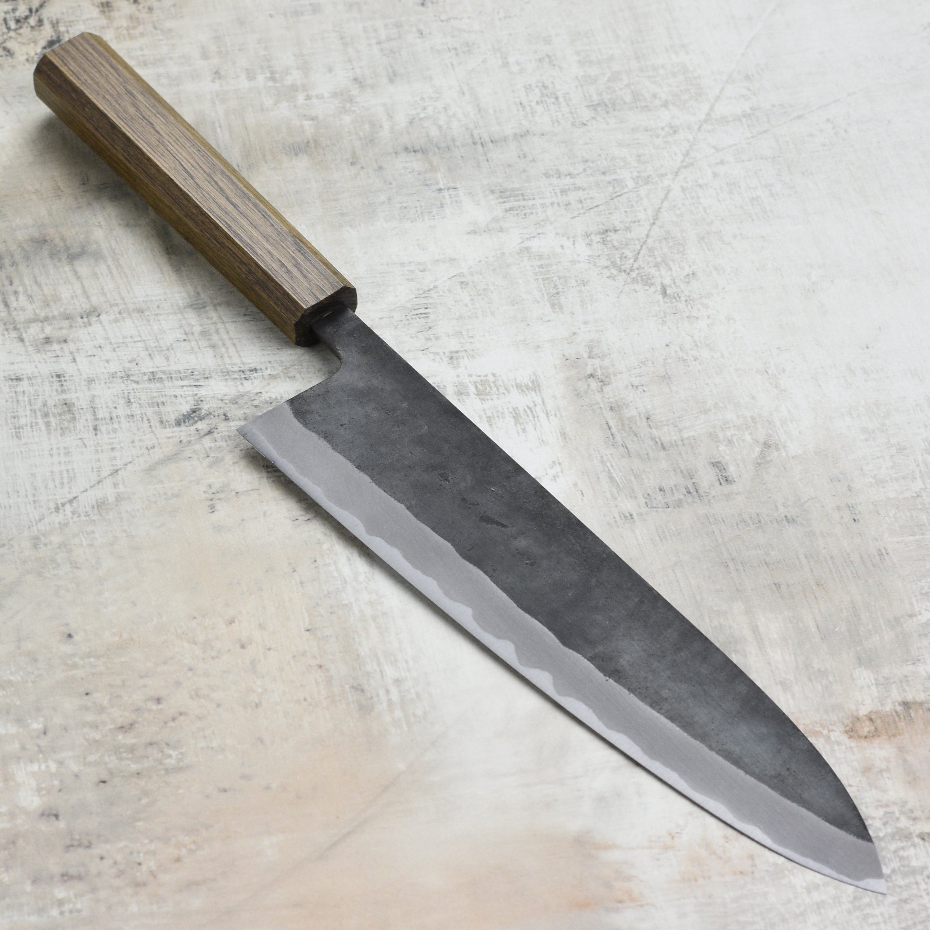 The Shiro Kamo Aogami Super Gyuto in action, expertly slicing through fresh vegetables.