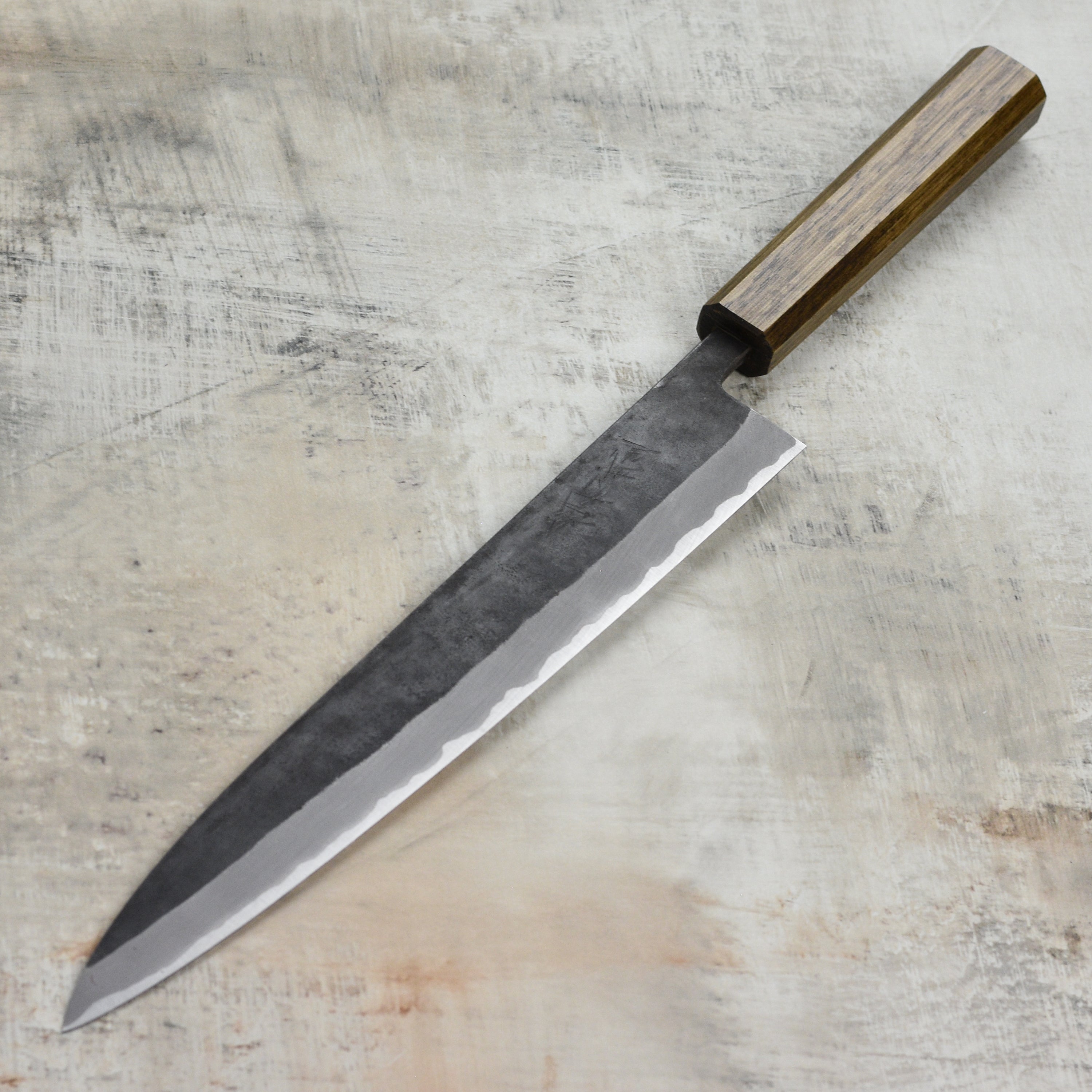 Shiro Kamo Aogami Sujihiki Knife showcasing its sharp edge and Kurouchi finish.