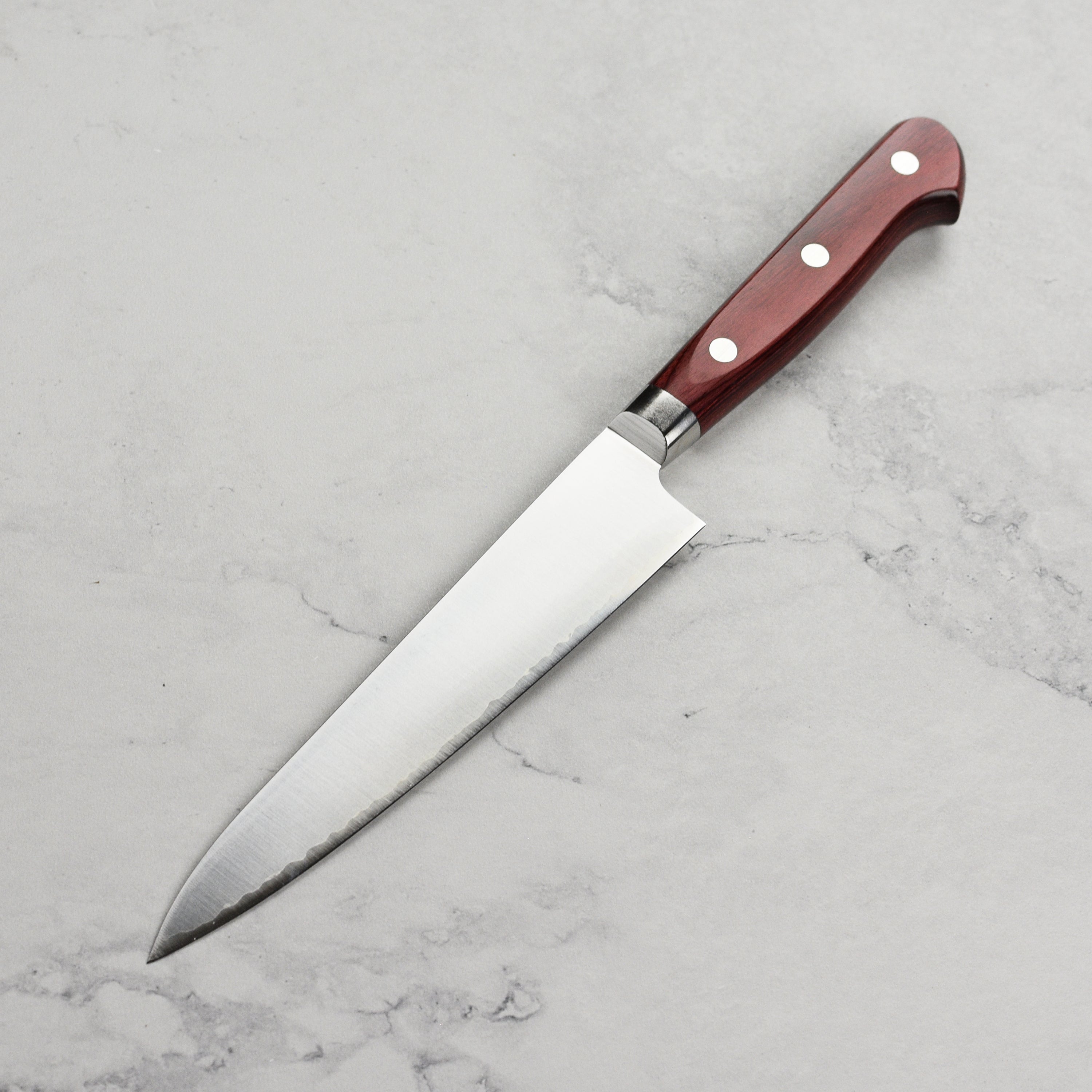 Close-up of the Takamura SG2 petty knife in action, slicing fresh vegetables.