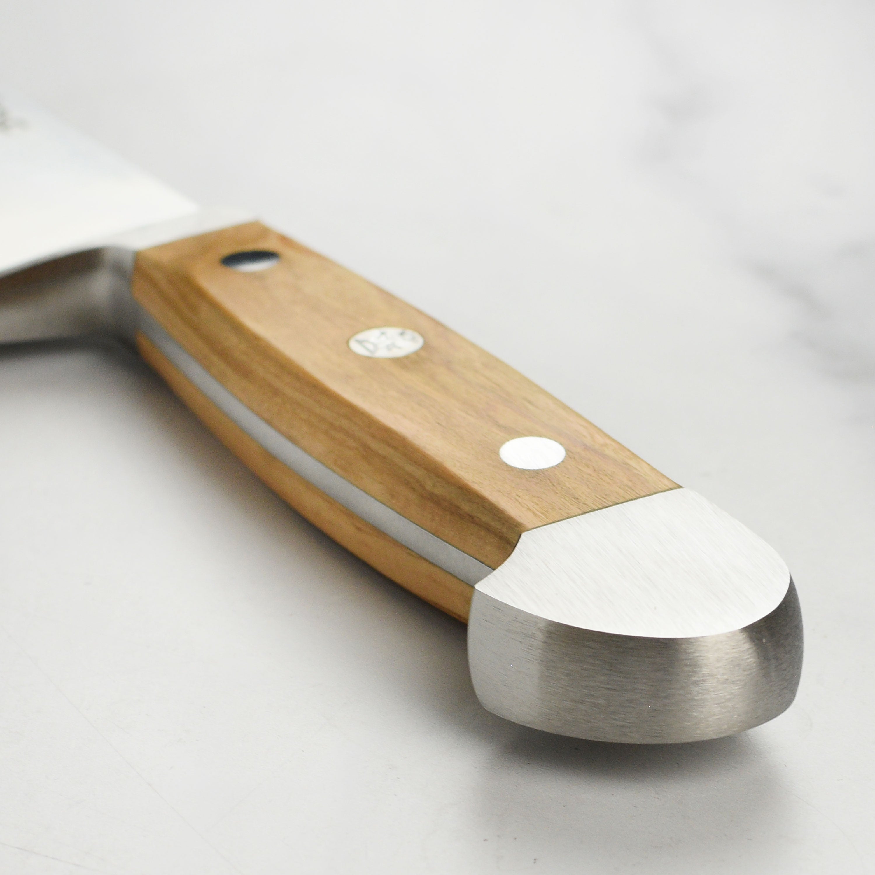 Close-up of the Gude Alpha Olive blade showing the high carbon steel finish and craftsmanship.