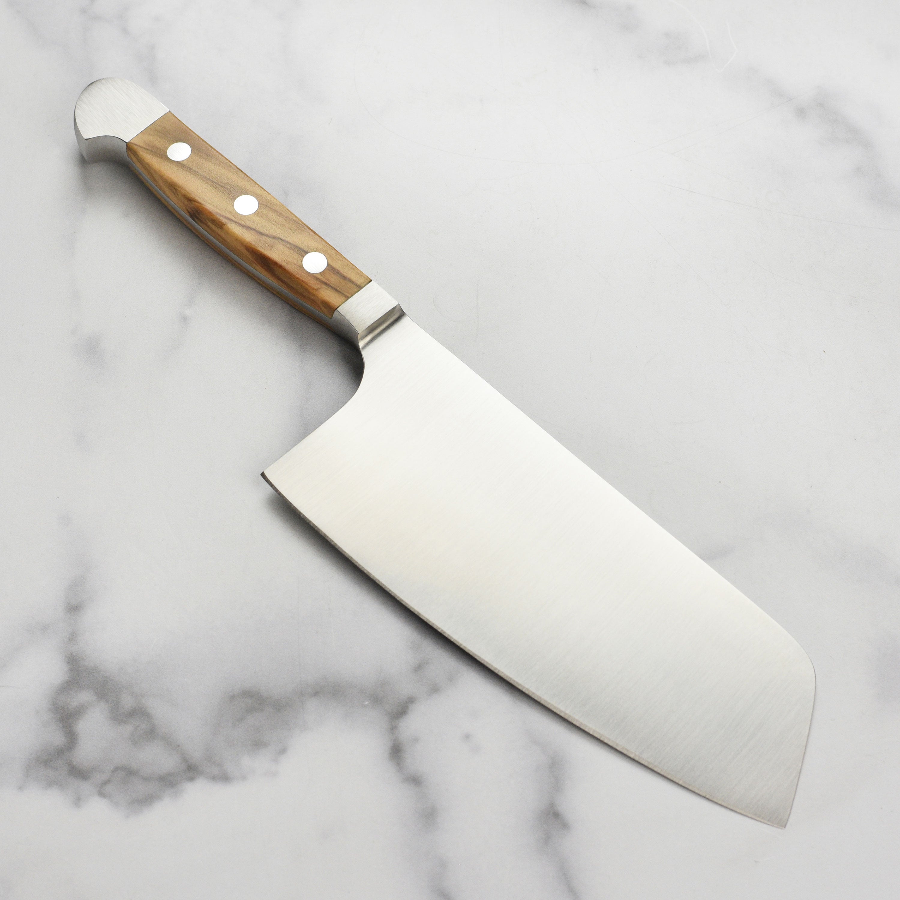 Detail shot of the handcrafted olive wood handle on the Gude Alpha chef knife