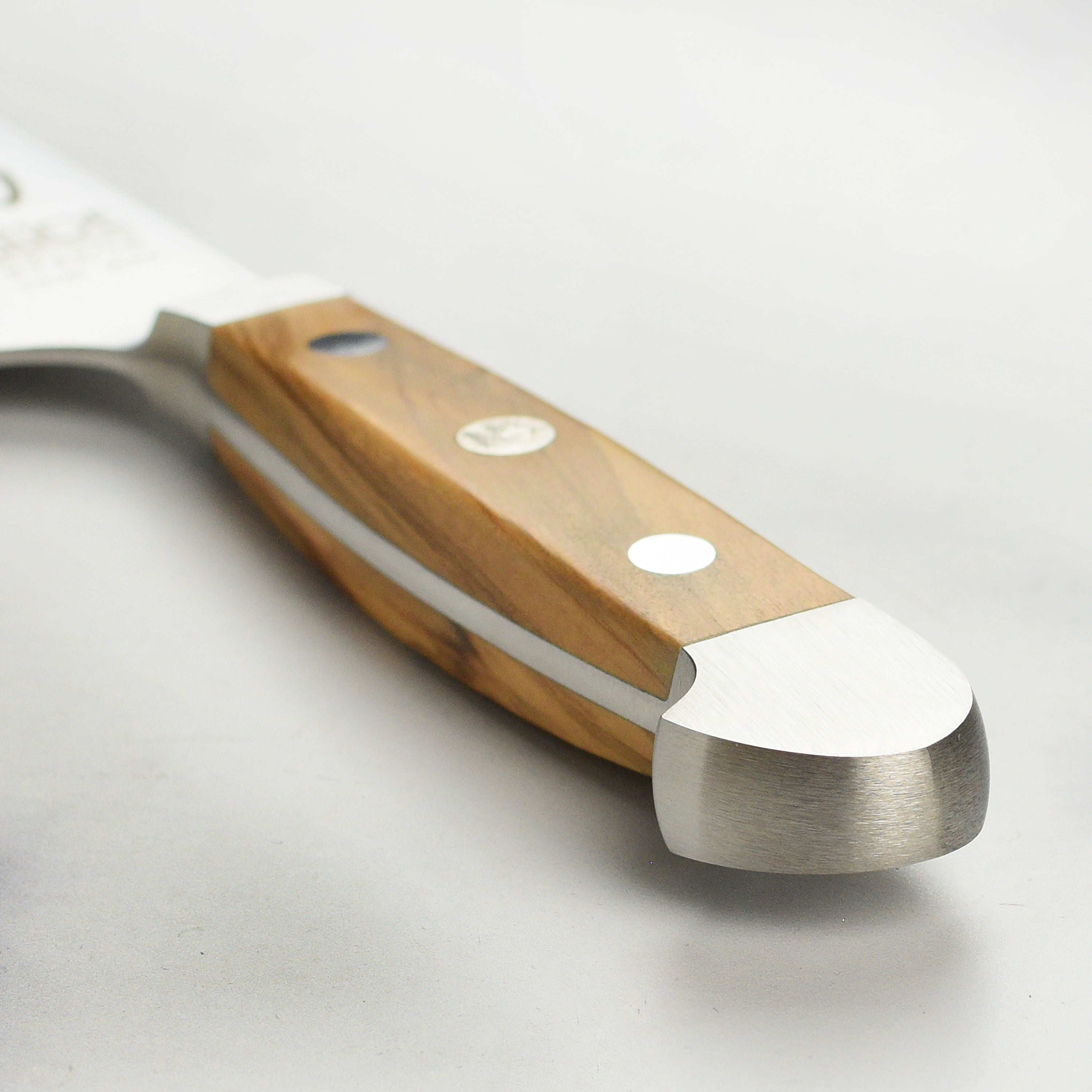 Detail shot of the handcrafted olive wood handle on the Gude Alpha chef knife
