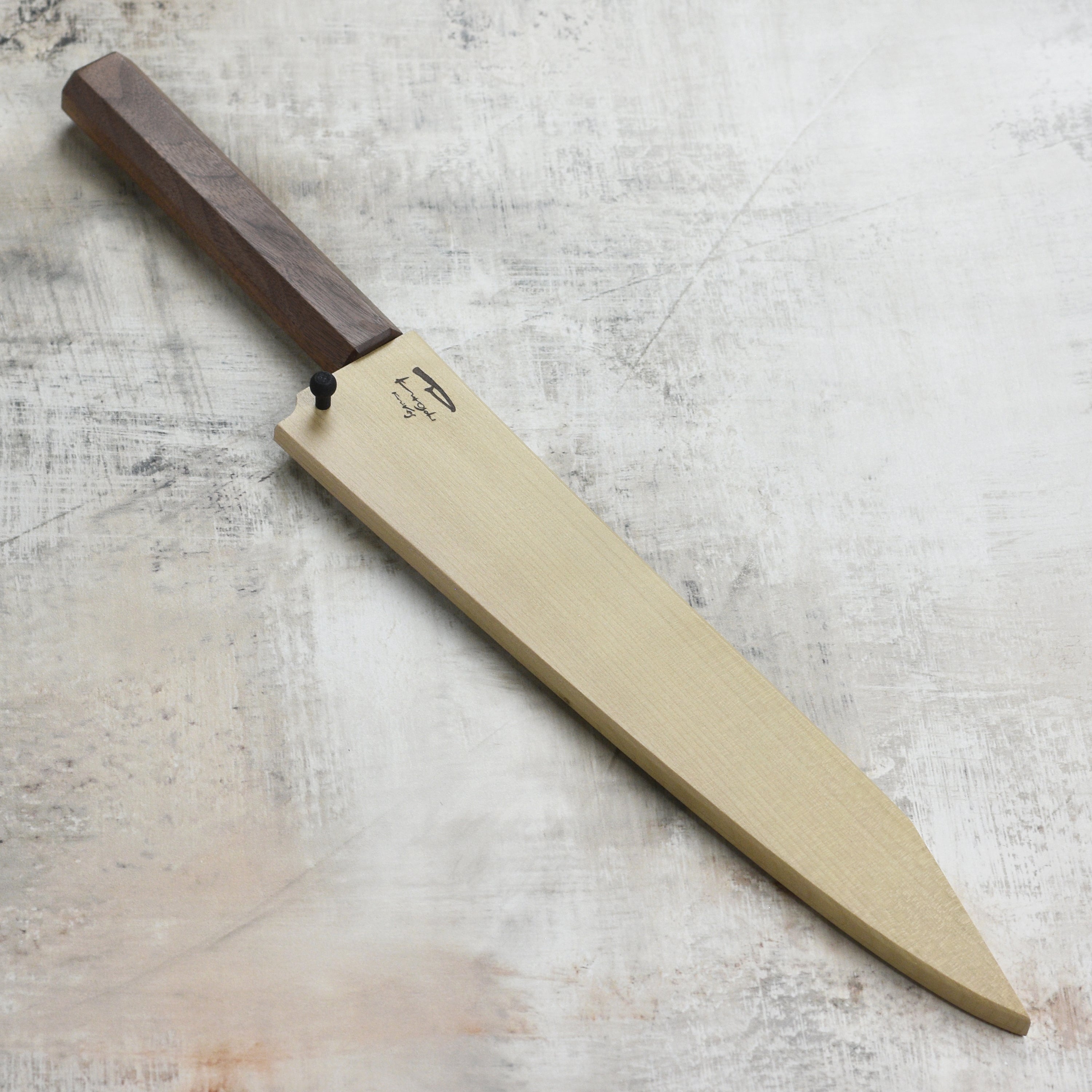 Front view of the Kurosaki Saya sheath on a Sujihiki knife in a kitchen setting