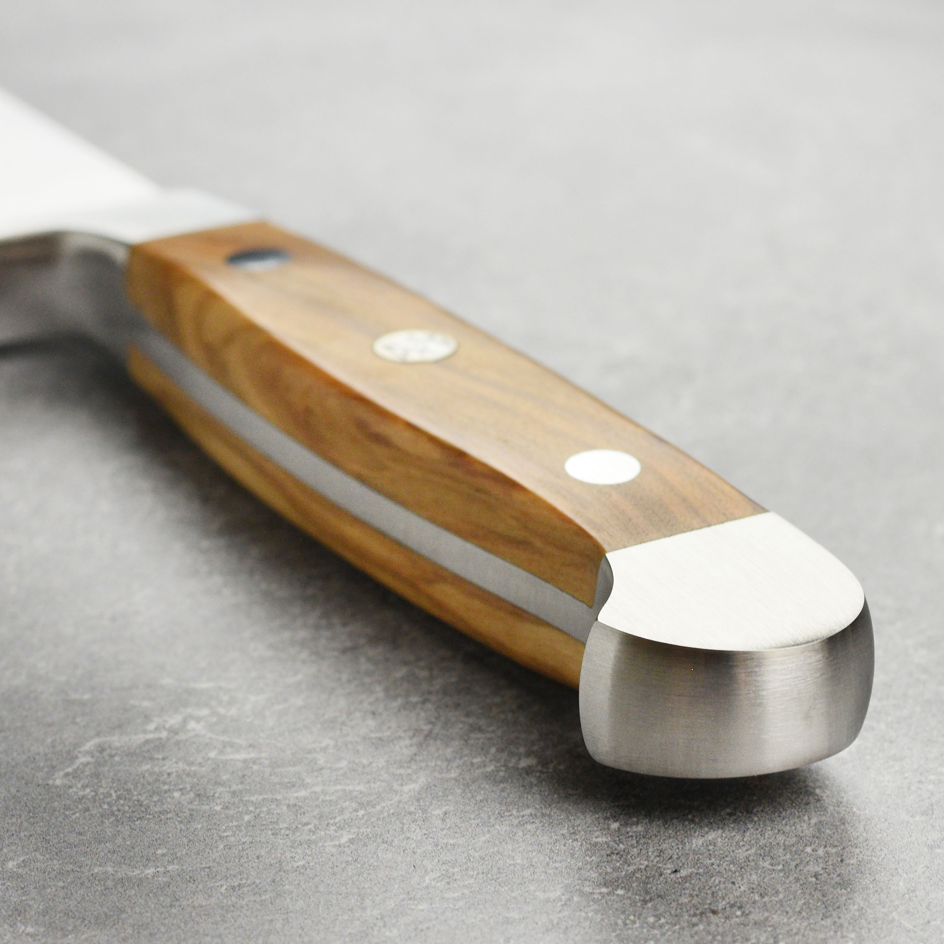 Chef using the large bread knife to slice a loaf of artisan bread in a kitchen