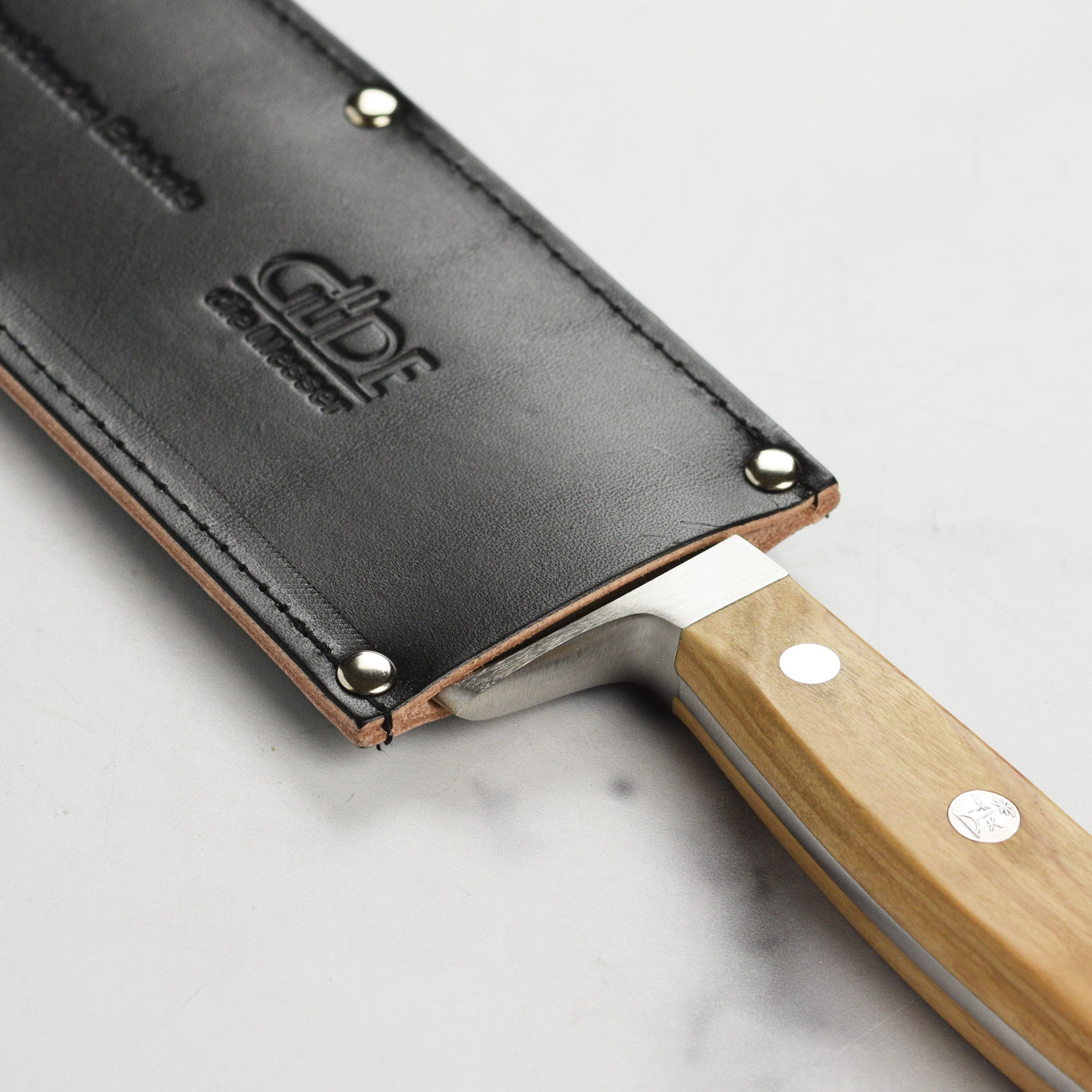 Full view of premium cowhide sheath laid next to German chef knife
