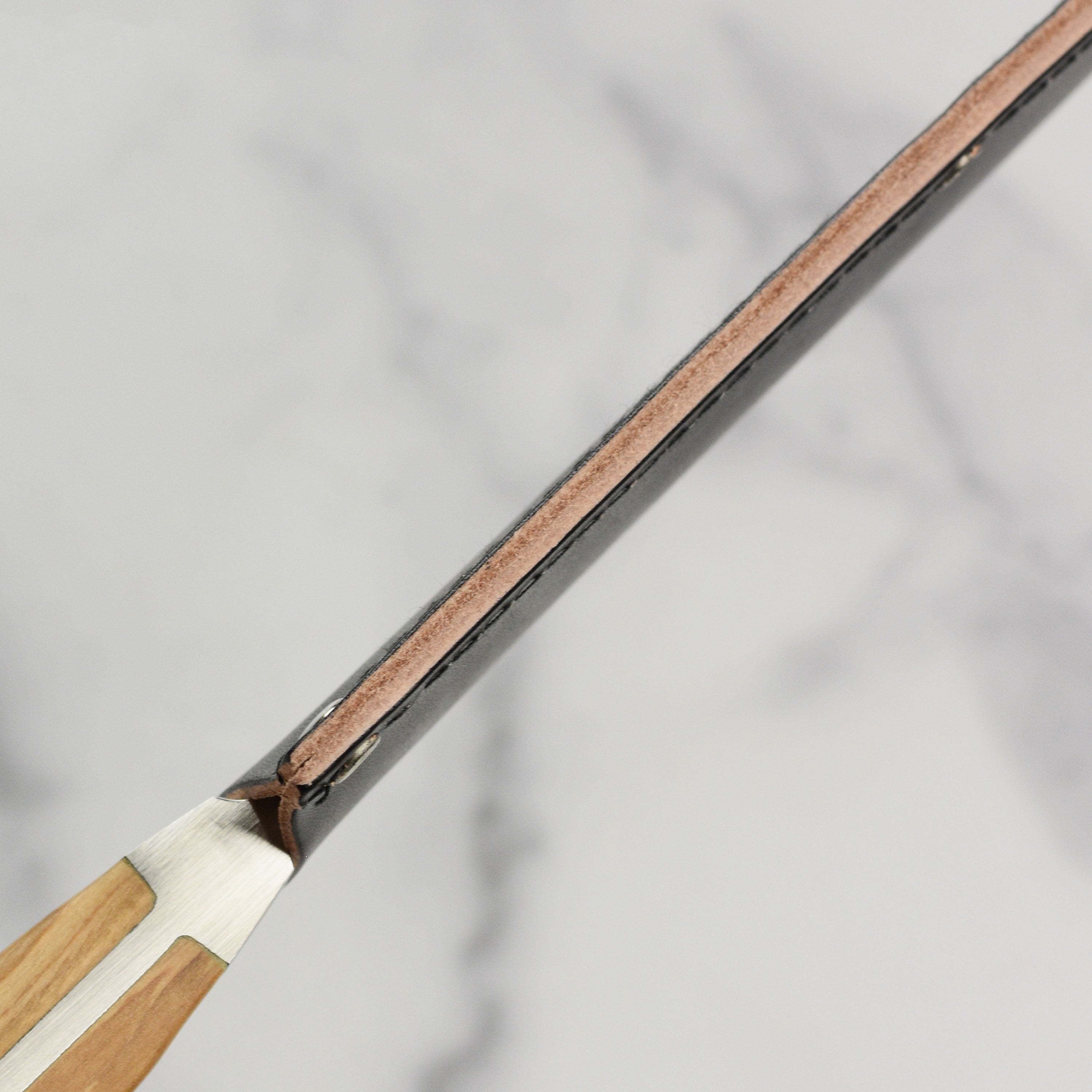 Angled close-up of leather blade protector showing stitching and texture