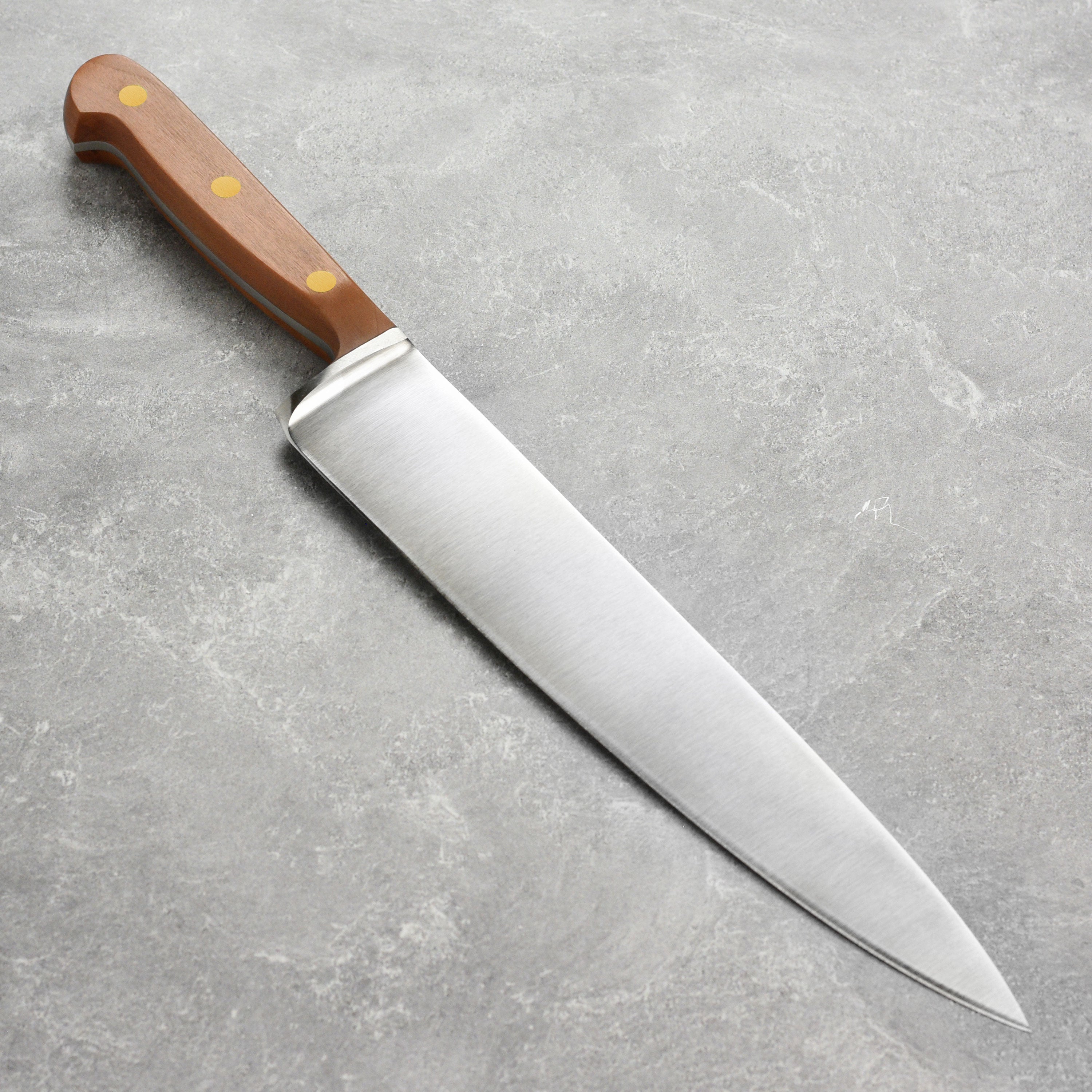 Detailed view of the handcrafted kitchen knife with plum wood handle and brass accents
