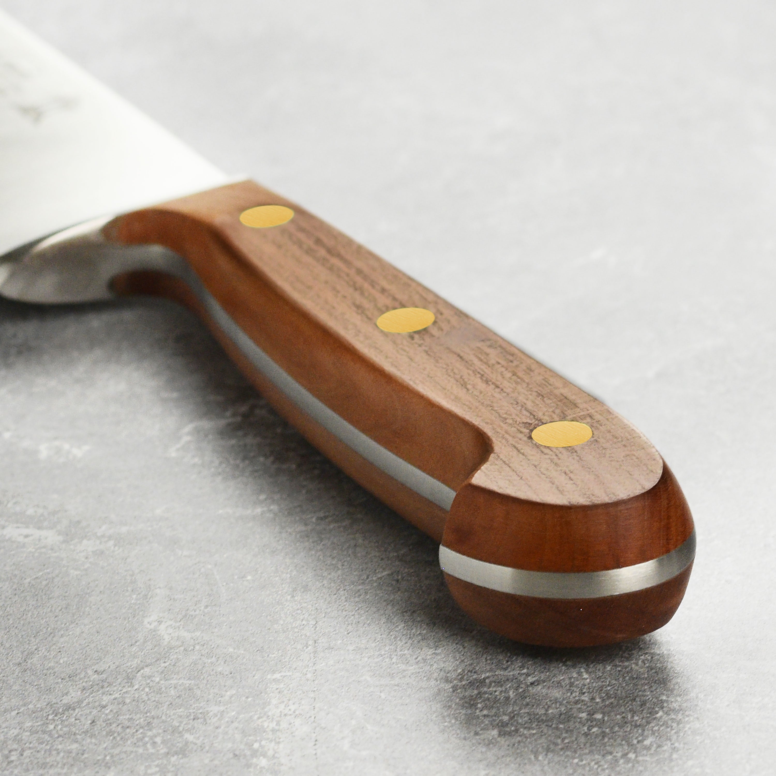 Detailed view of the handcrafted kitchen knife with plum wood handle and brass accents