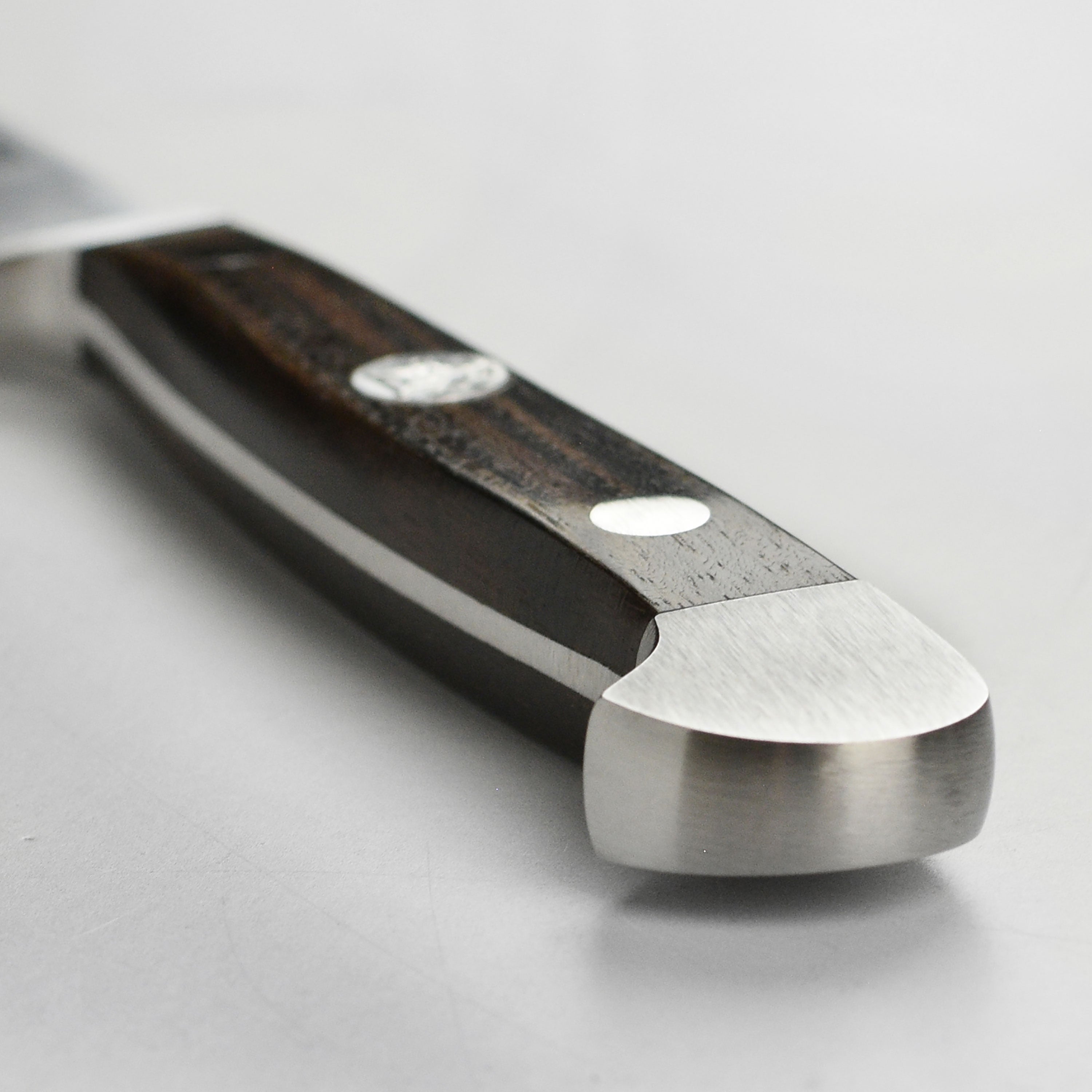 Close-up view of the Gude Alpha paring knife highlighting the dual bolster design and sharp edge.
