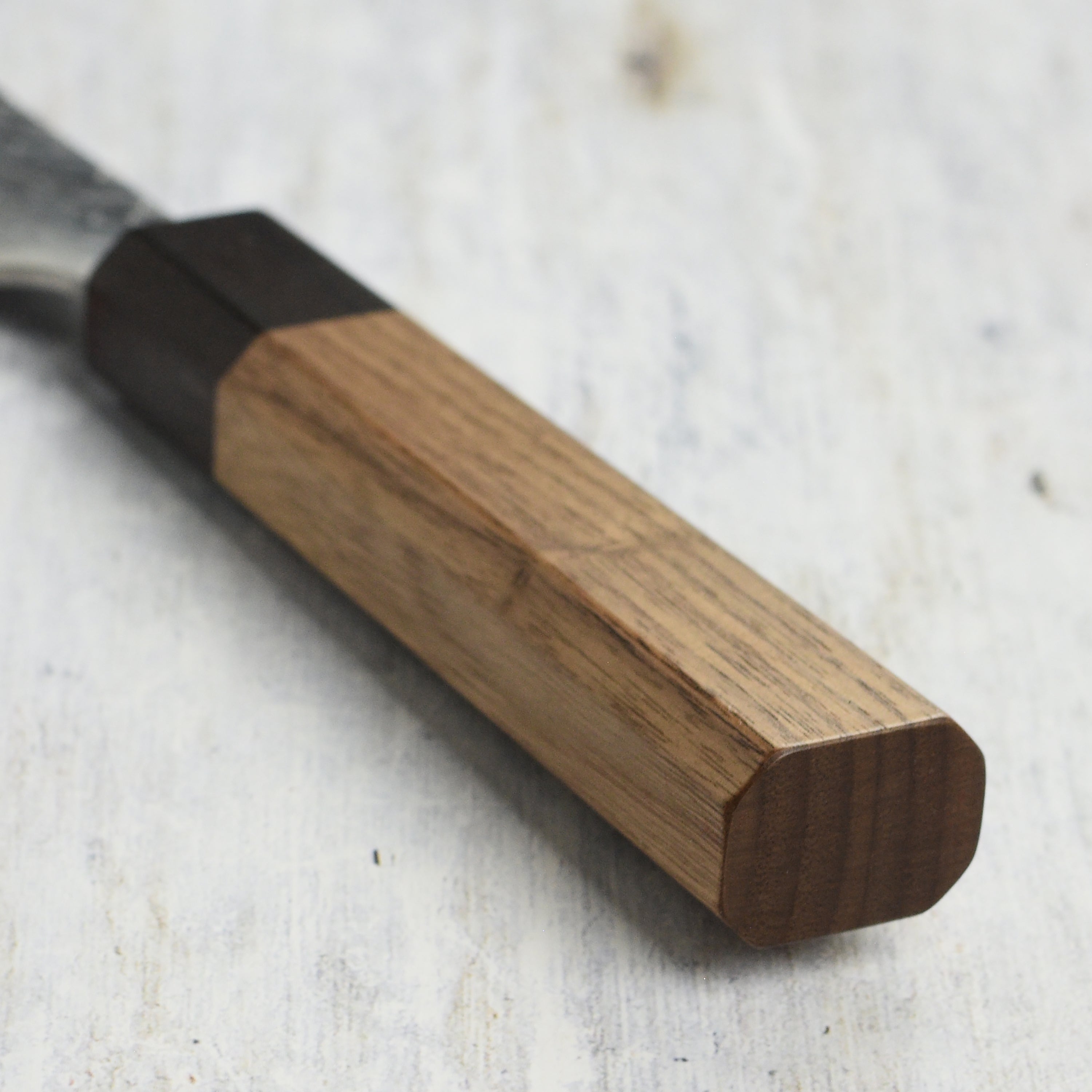 Side view of handmade Japanese kitchen knife highlighting walnut wood octagonal handle
