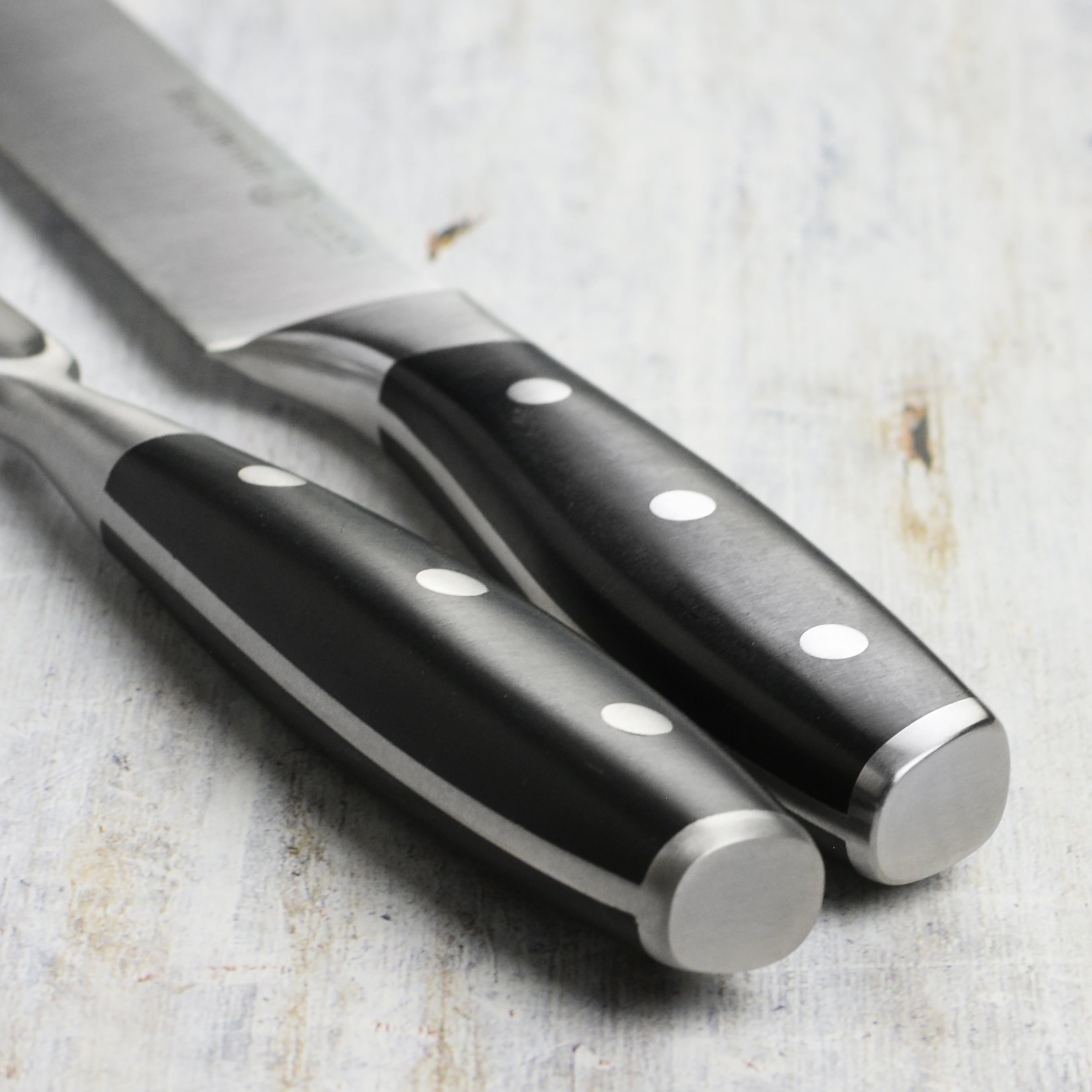 Chef slicing meat with professional carving knives in a kitchen setting