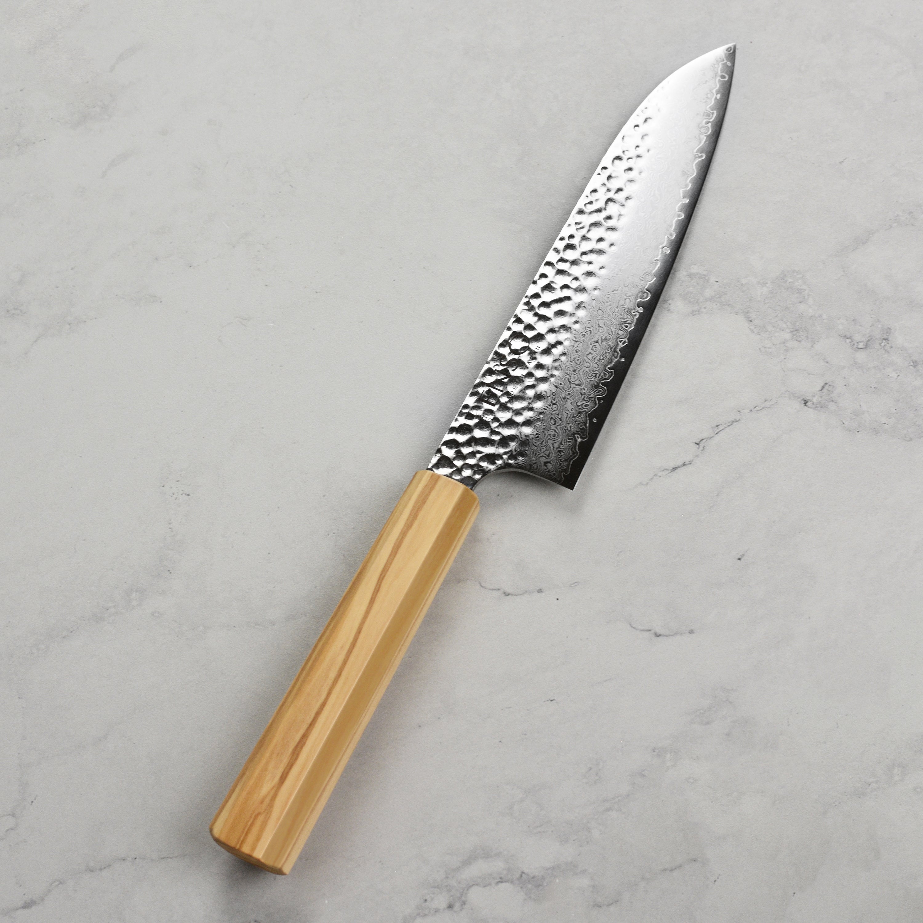 Enso Olivewood Santoku knife in action, slicing fresh vegetables on a cutting board.
