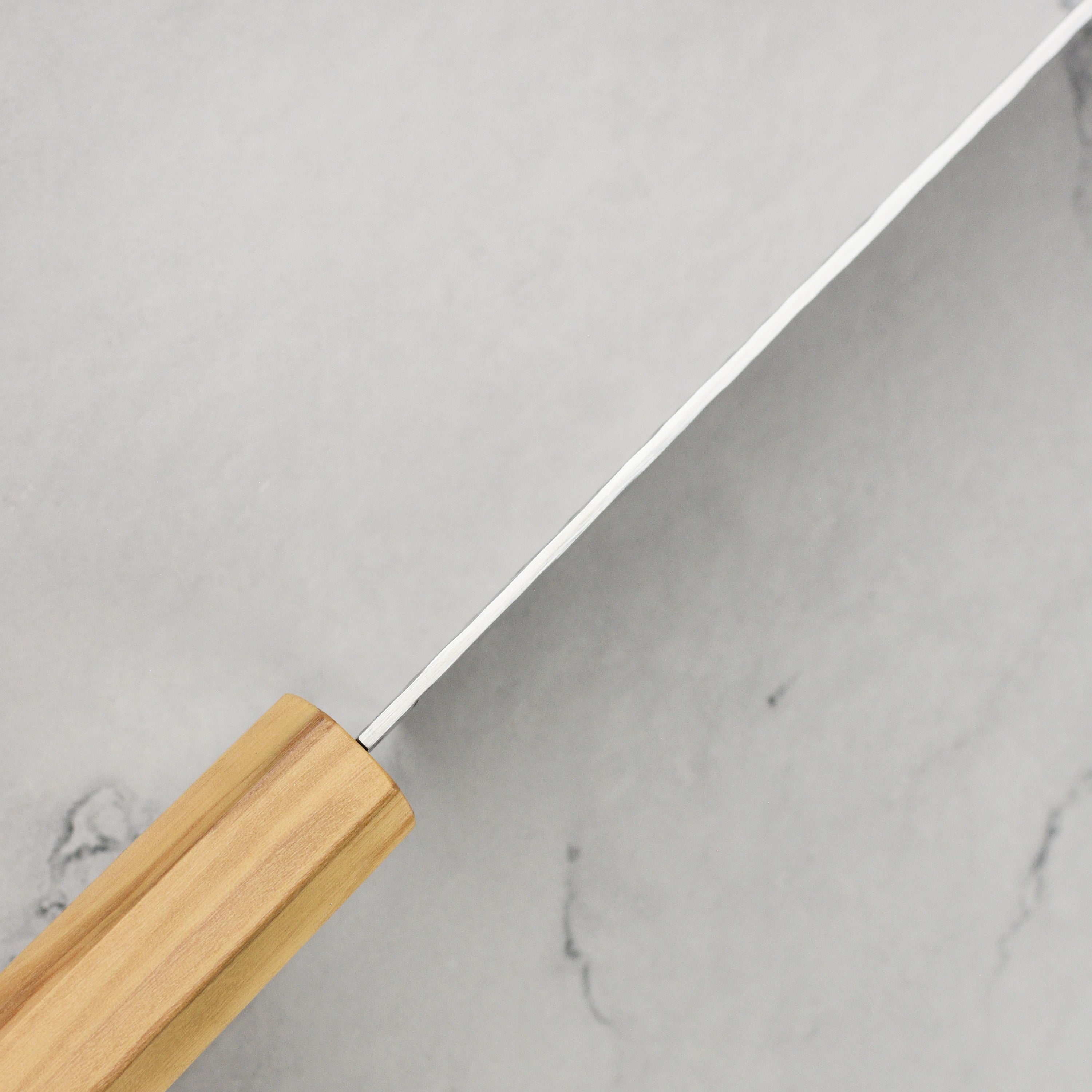 Enso Olivewood Santoku knife in action, slicing fresh vegetables on a cutting board.
