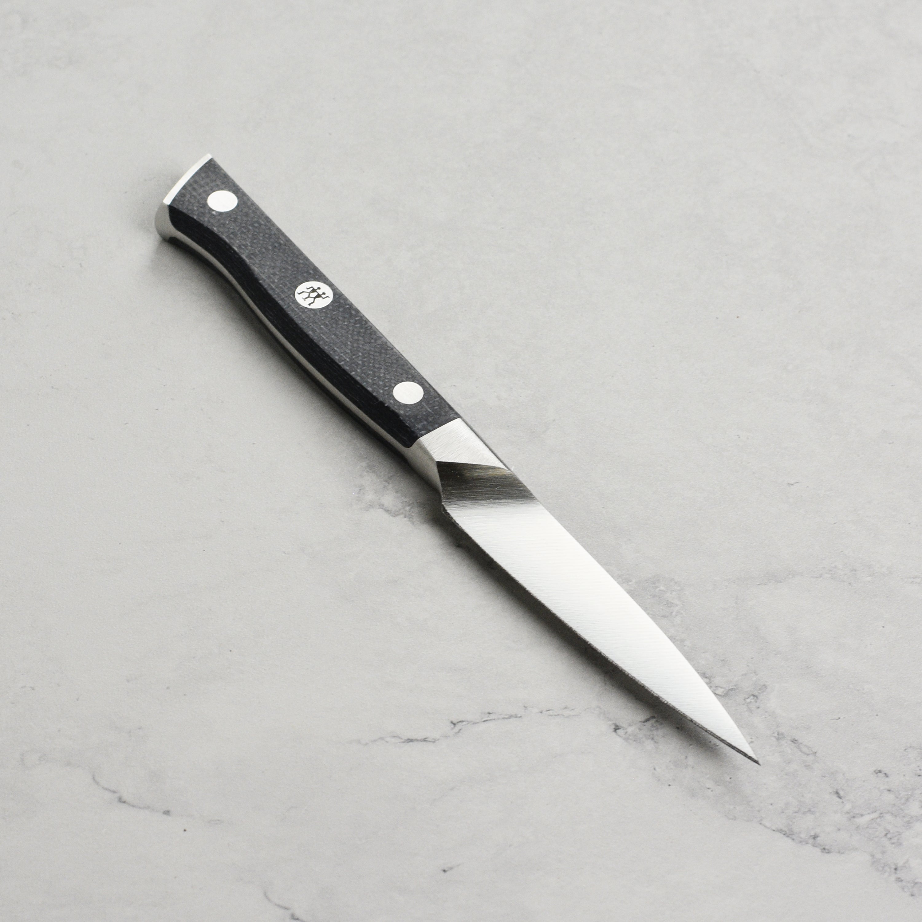 Zwilling Spectrum 4" paring knife in use, effortlessly slicing fruits and vegetables on a wood cutting board.