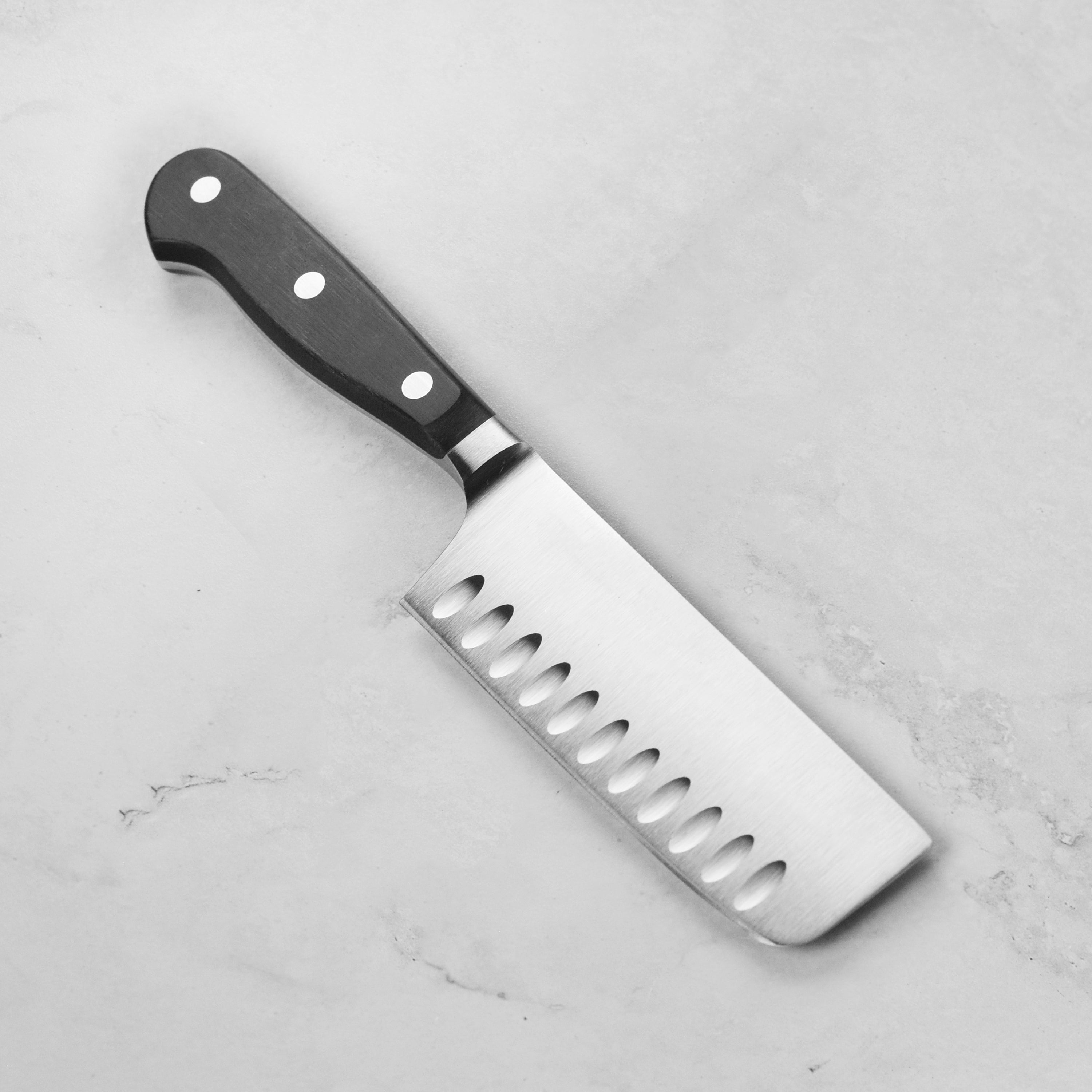 Close-up of the knife cutting assorted vegetables — showcasing precision and clean slices