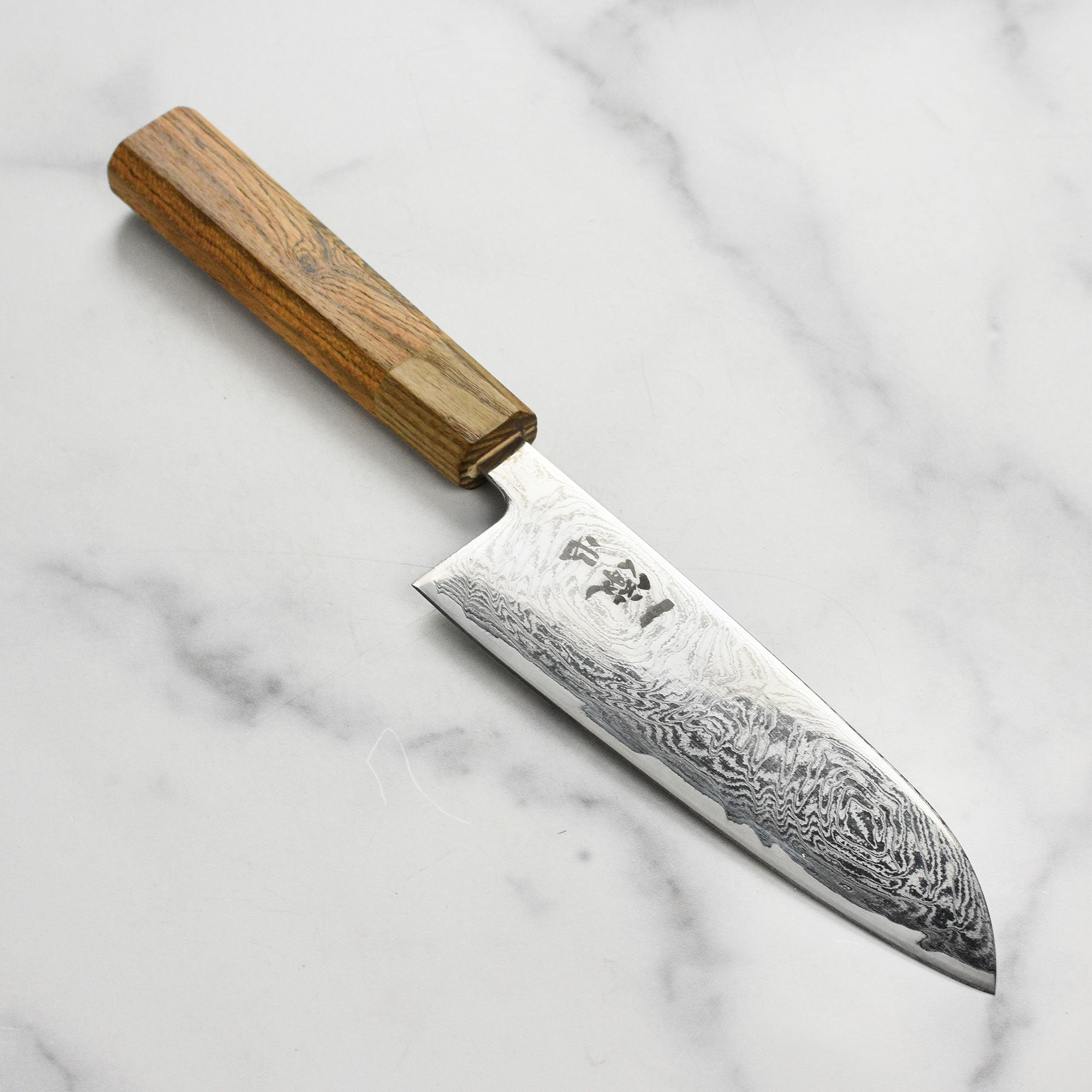 Ittetsu AUS10 Spiral Damascus Santoku Knife on a wooden cutting board, showcasing its sharp blade and ergonomic handle.