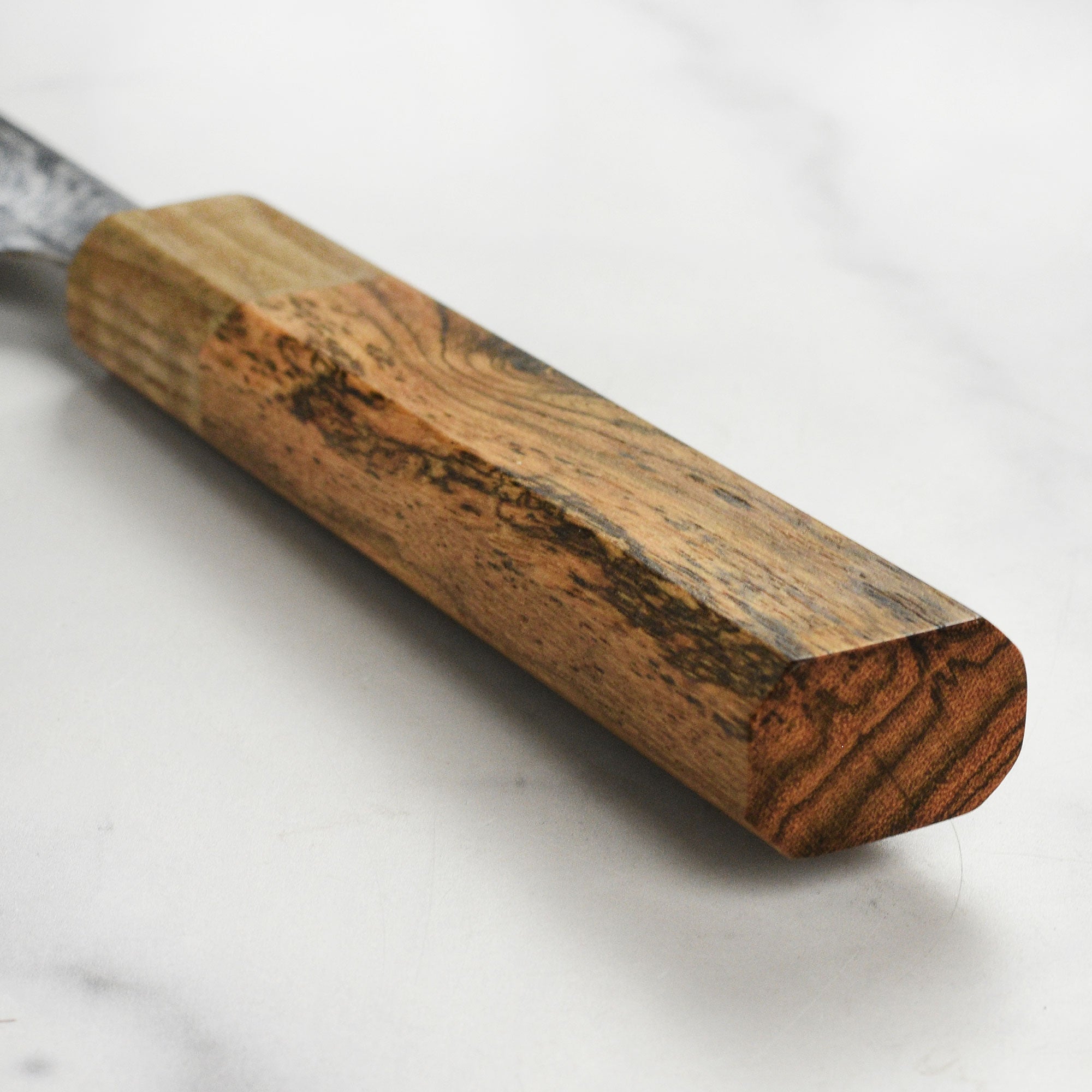 Close-up of the Ittetsu Santoku knife demonstrating the intricate spiral Damascus pattern on the blade.