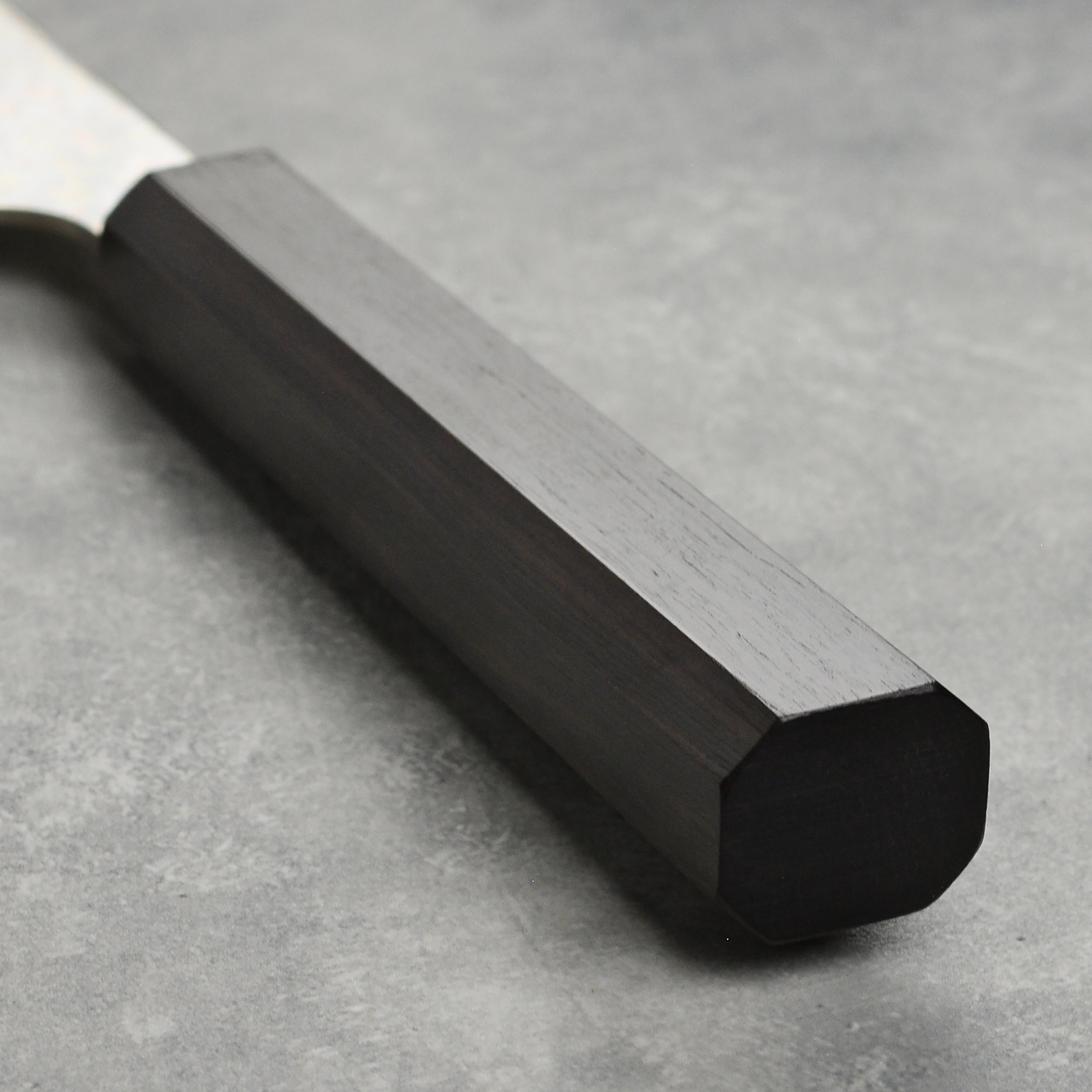 Close-up of the ebony wood handle of the Saji Bunka Chef Knife, highlighting its elegant design.