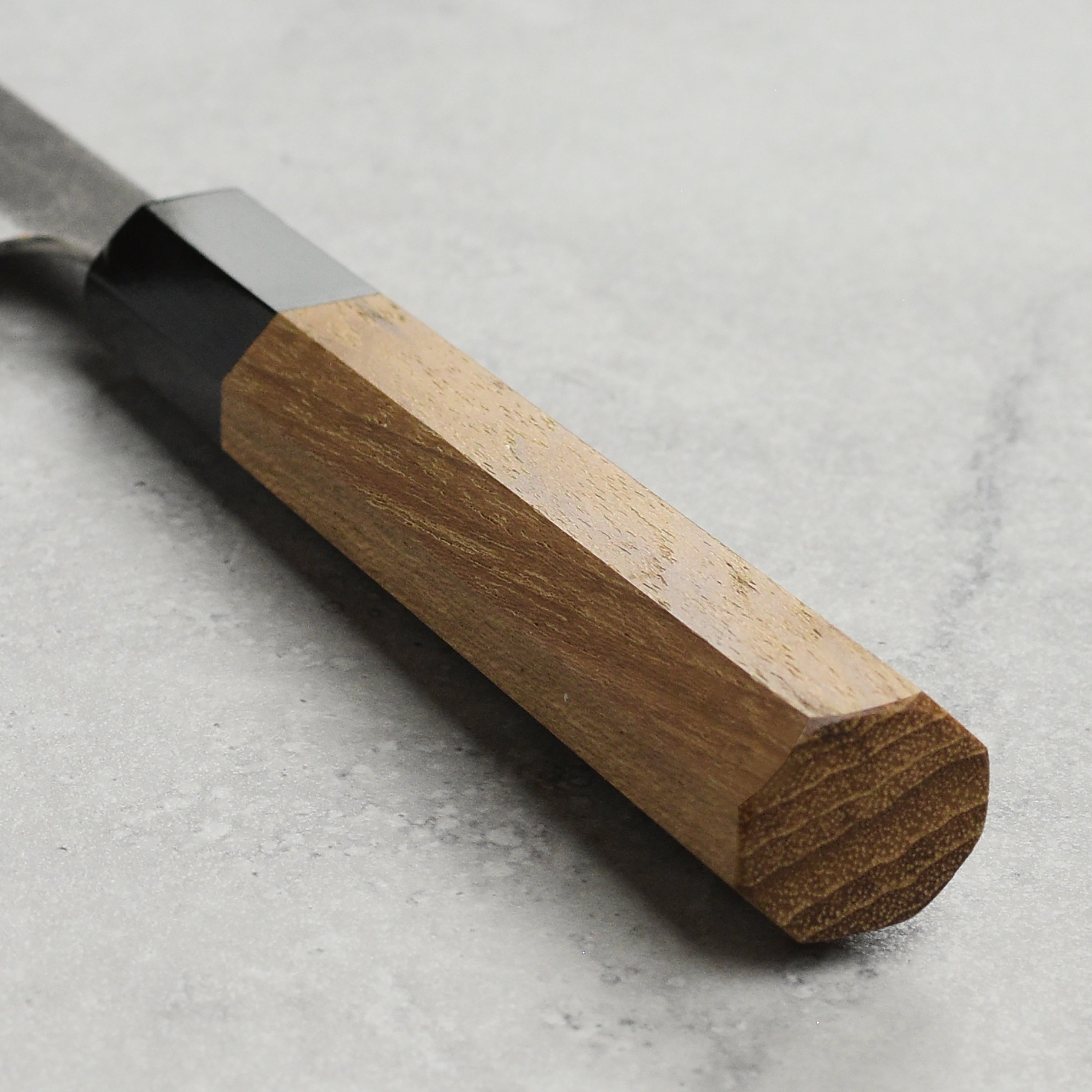 Teak wood handle of the Enso carbon steel petty knife highlighting its craftsmanship.
